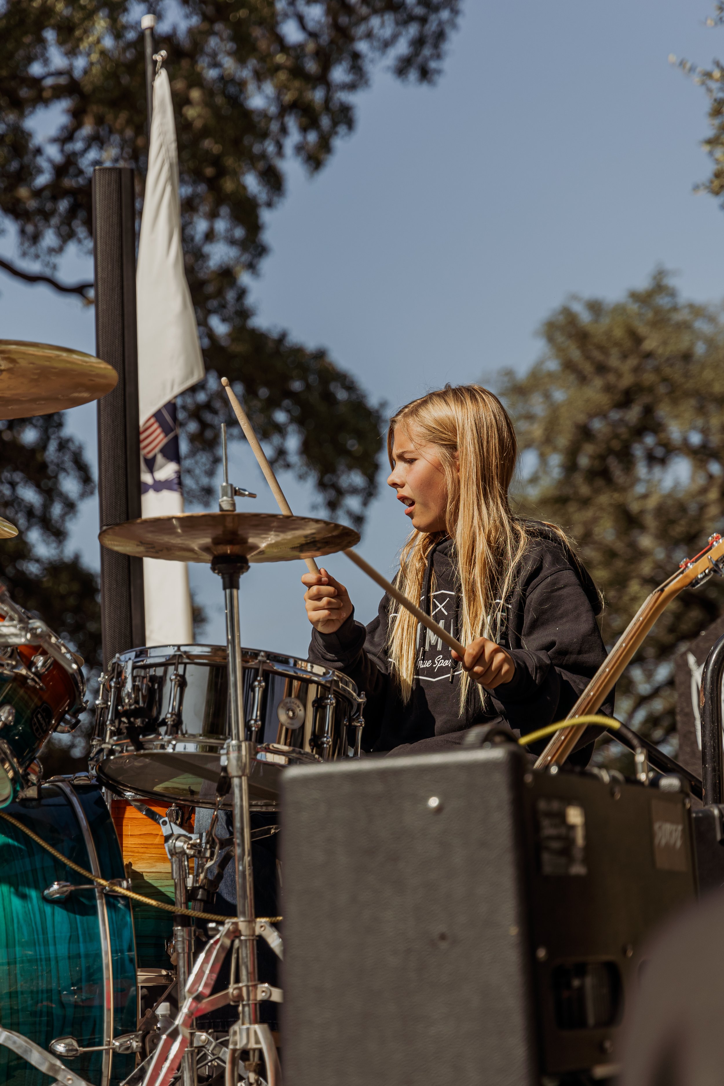 Young girl playing the drums outdoors during daytime.