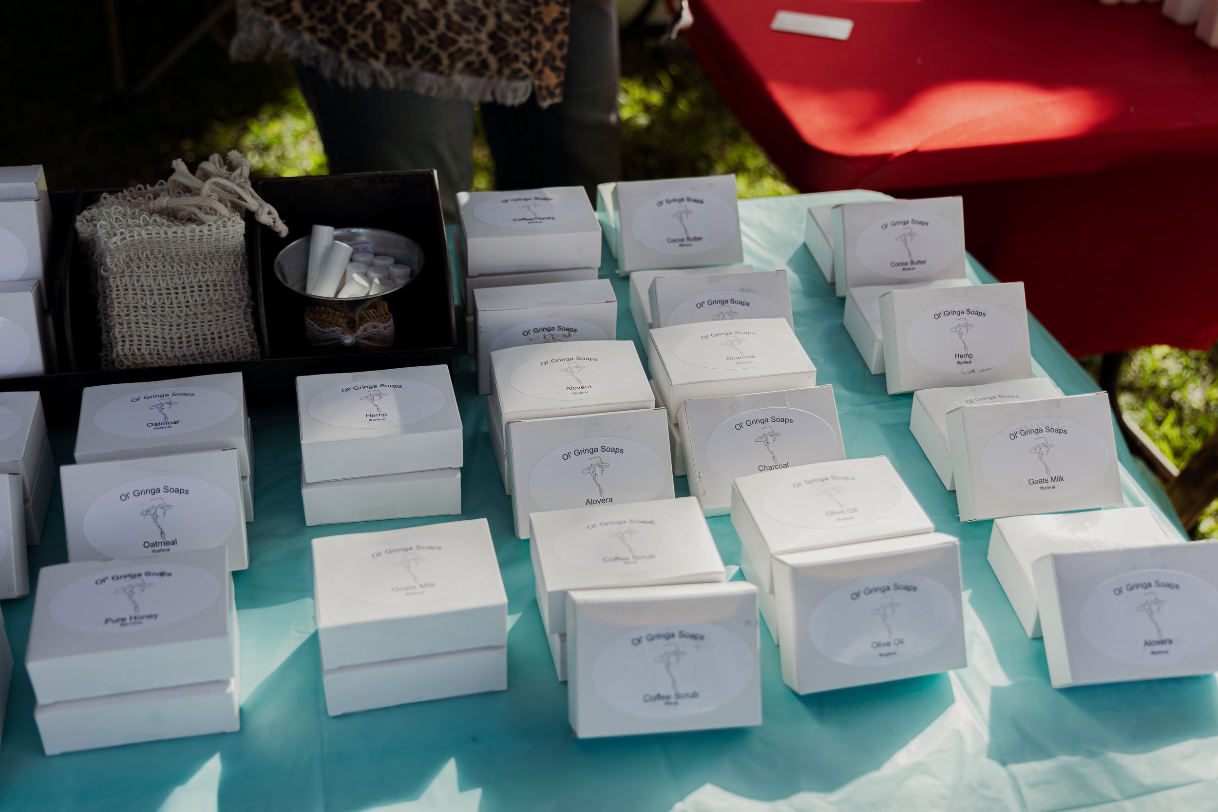 Table with white boxes labeled 'Oil Gringa Soaps' containing various soap flavors