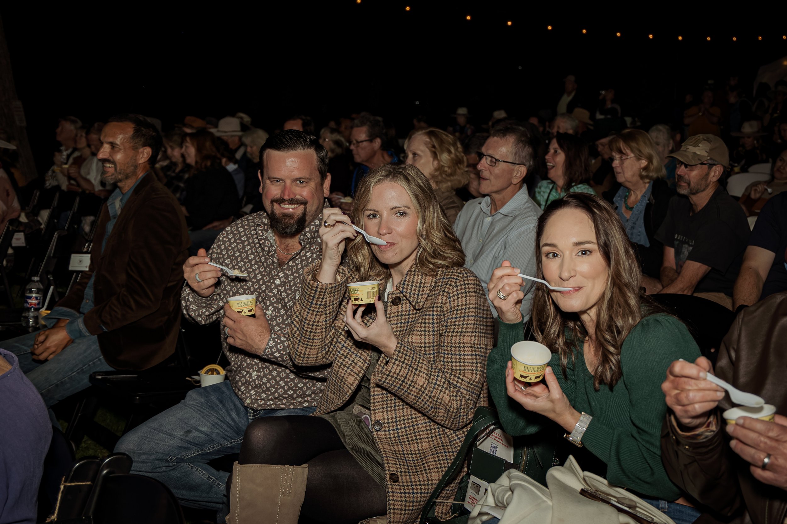 Group of people sitting at an event, enjoying ice cream.