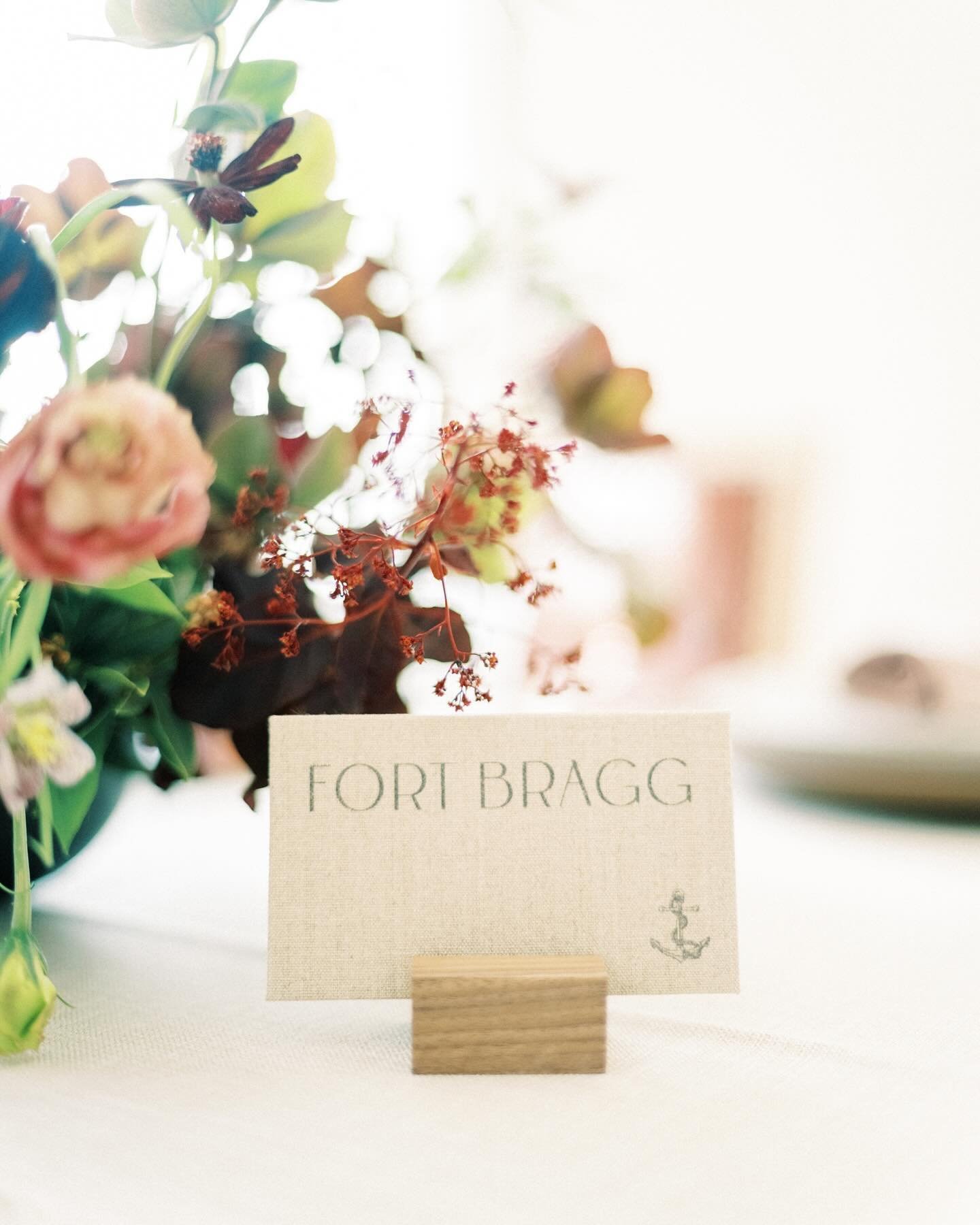 Instead of traditional table numbers, Janessa and James opted to name their tables with locations that held meaning for them as a couple. Each was printed on linen, and mounted in simple wooden stand.
.
Planning + Design | @teagueevents⁠
Photography 