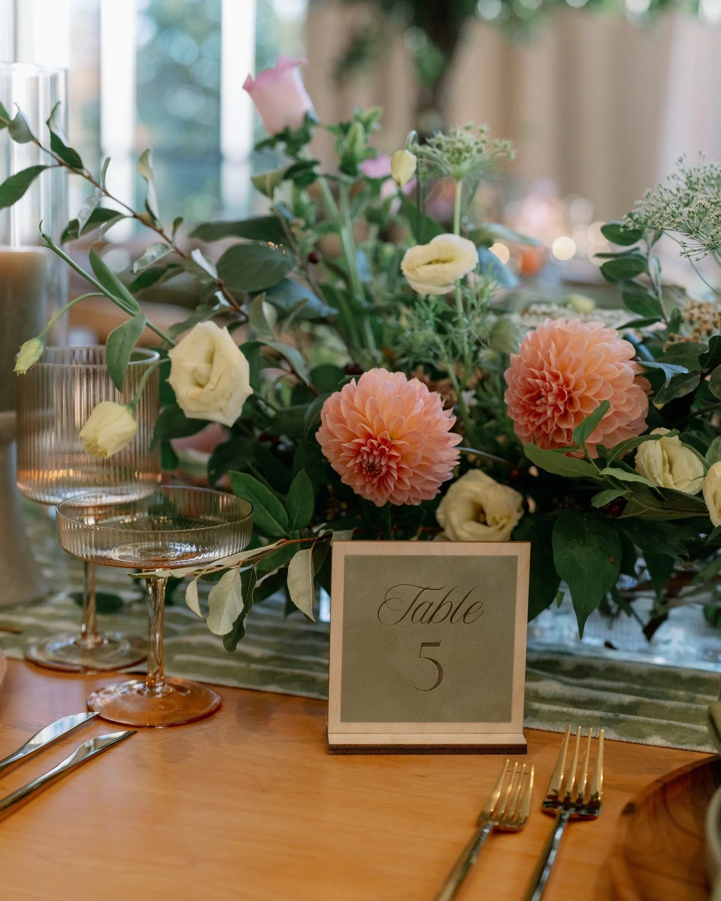 When the woods come indoors, every detail feels alive. Tess and Michael&rsquo;s reception, we designed pocketed floral menus pressed in letterpress, each wrapped with a colored band to subtly signal meal choice. Wooden table numbers tied the story to