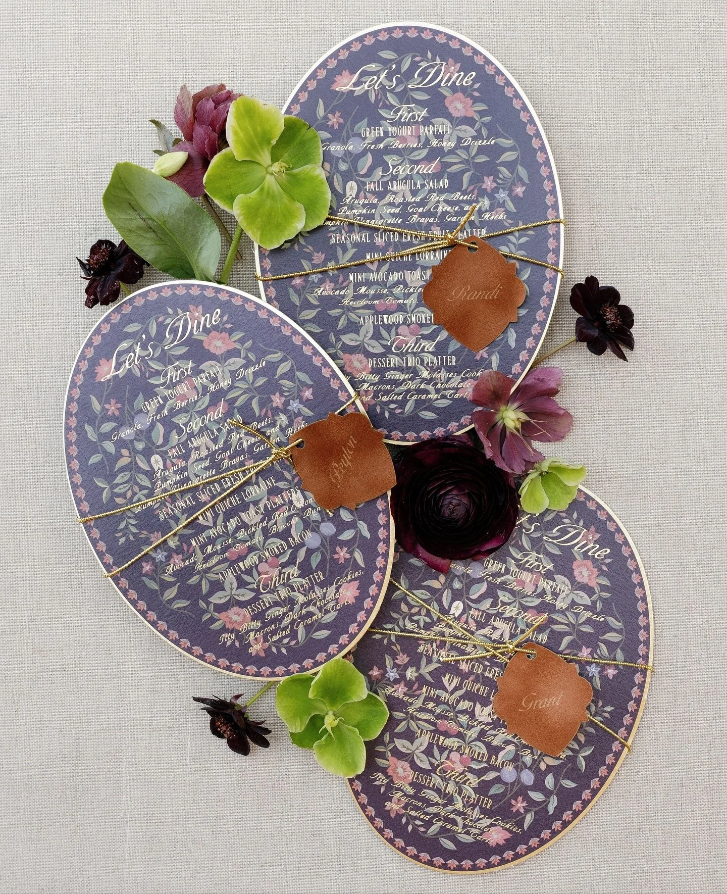 Autumn tones, moody florals, and gold foil that catches the light just right. These oval menus shimmer with texture, paired with velvet place cards engraved and tied in gold cord for a touch of quiet luxury.⁠
.⁠
Photography | @jeffbrummettphotography