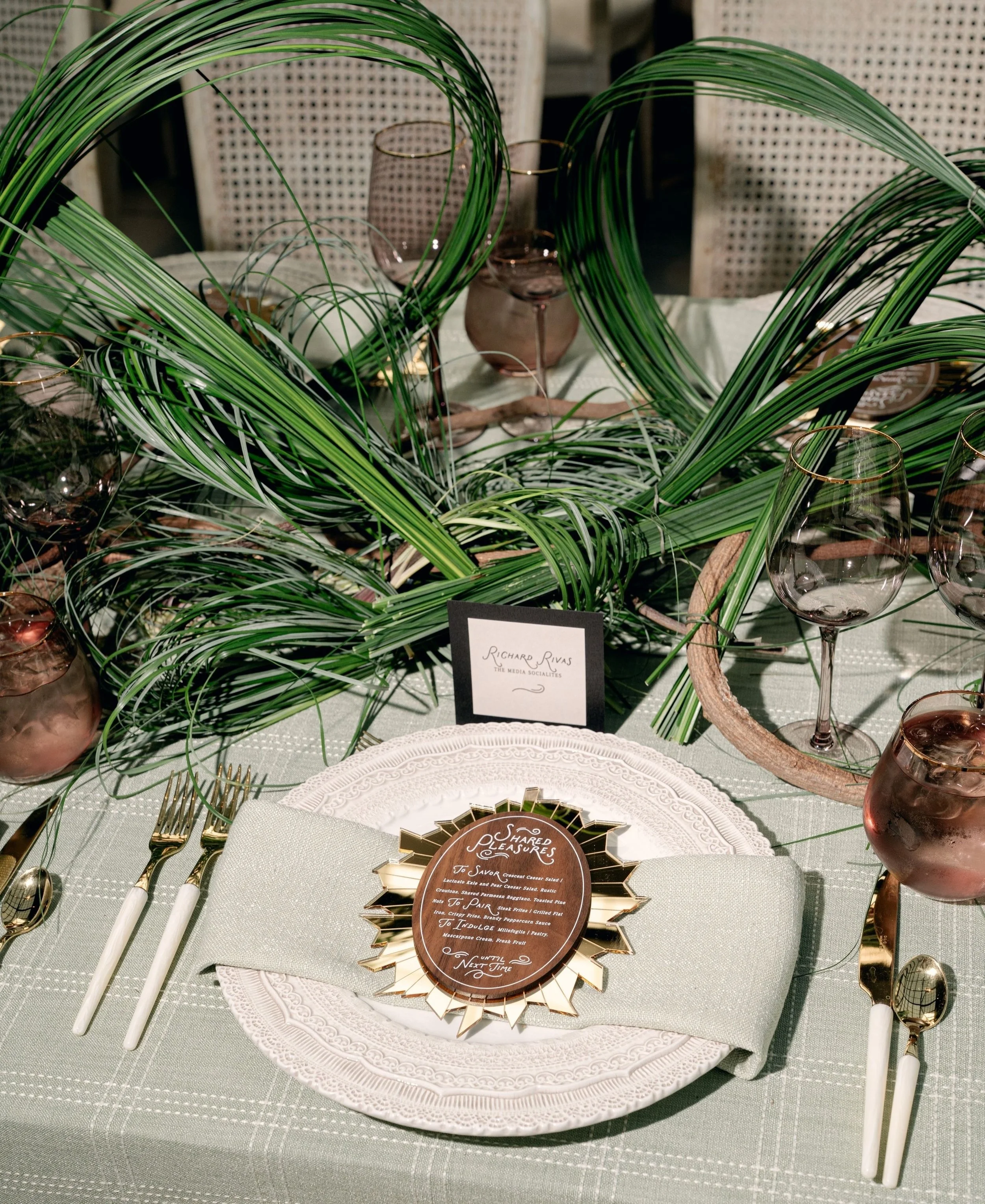 A girl dinner&ndash;style luncheon with a playful point of view, where the paper set the tone. Real wood menus featured whimsical typography and were layered over broken mirror&ndash;inspired gold acrylic backers, adding contrast, texture, and a litt