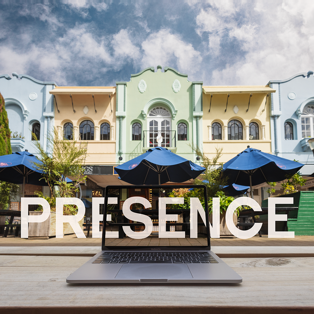 A stunning row of pastel coloured art deco shopfronts with decorative architectural stained glass windows and balconies with wrought iron ballustrades - in New Regent Christchurch NZ_the word presence is white letters over a laptop