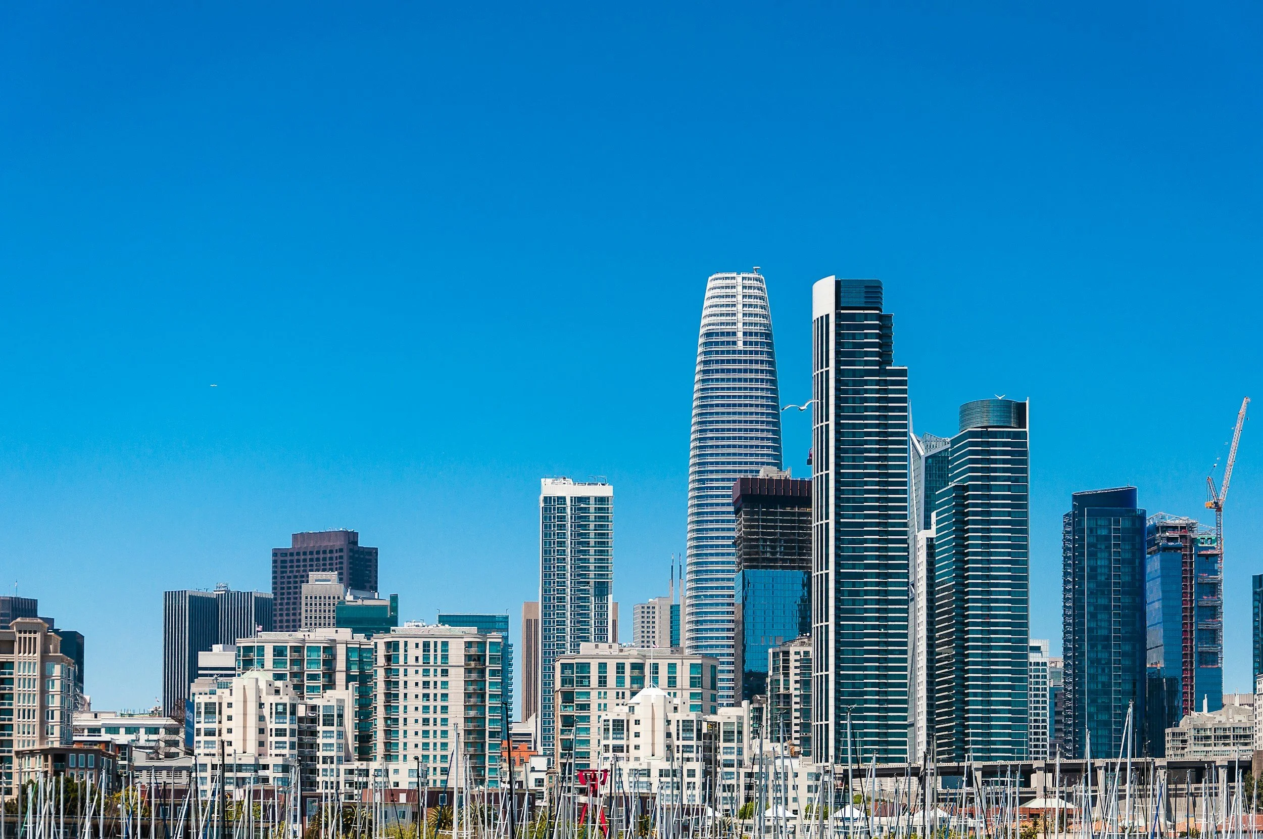 Skyline view of downtown San Francisco with various skyscrapers and a marina with sailboats in the foreground.