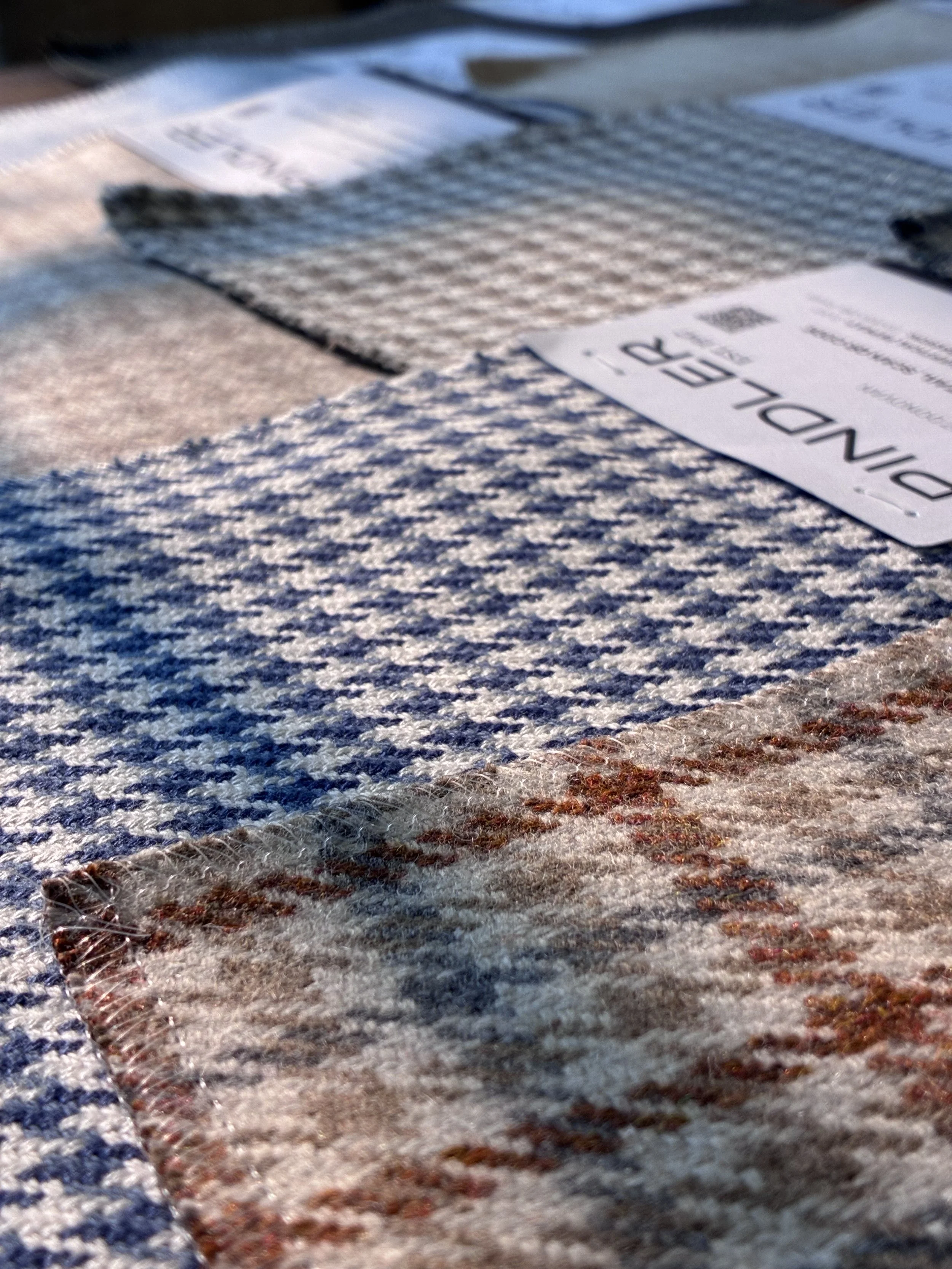 Close-up of intricately woven fabrics with geometric patterns, one in dark ink on a light background, and another in light color with darker designs.