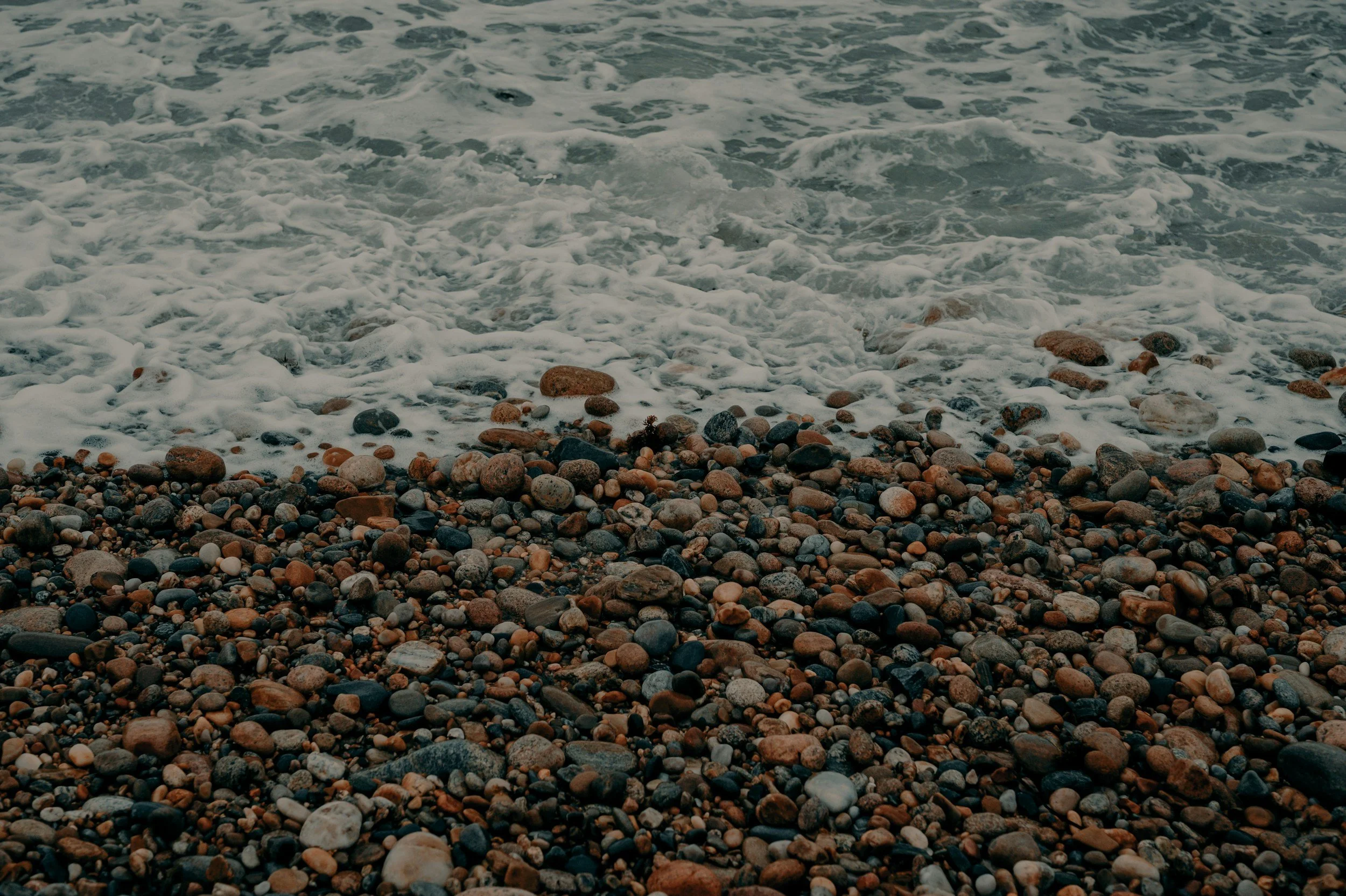 Ocean waves gently washing over a colorful pebble beach.