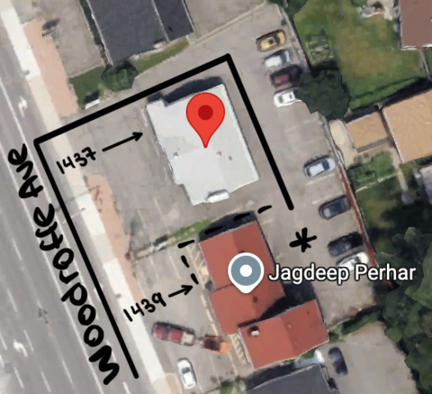 Aerial view of the property on Woodroffe Ave with a white roofed building and red-roofed building, marked with directions to the building's parking, showing nearby parked cars.
