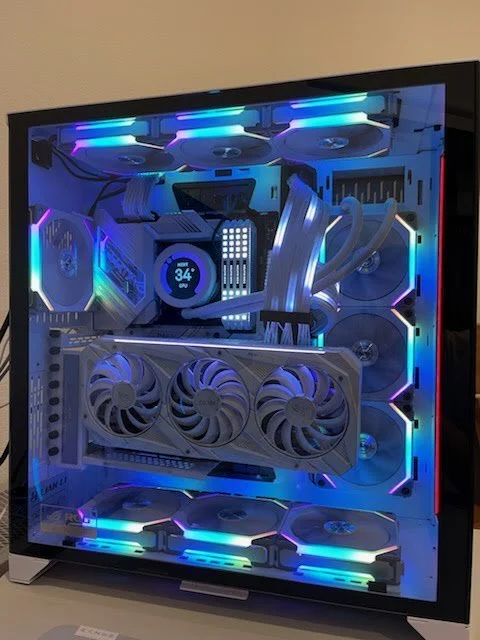 A high-end gaming PC with RGB lighting inside a transparent case, featuring cooling fans, a large graphics card, and multiple cooling components.