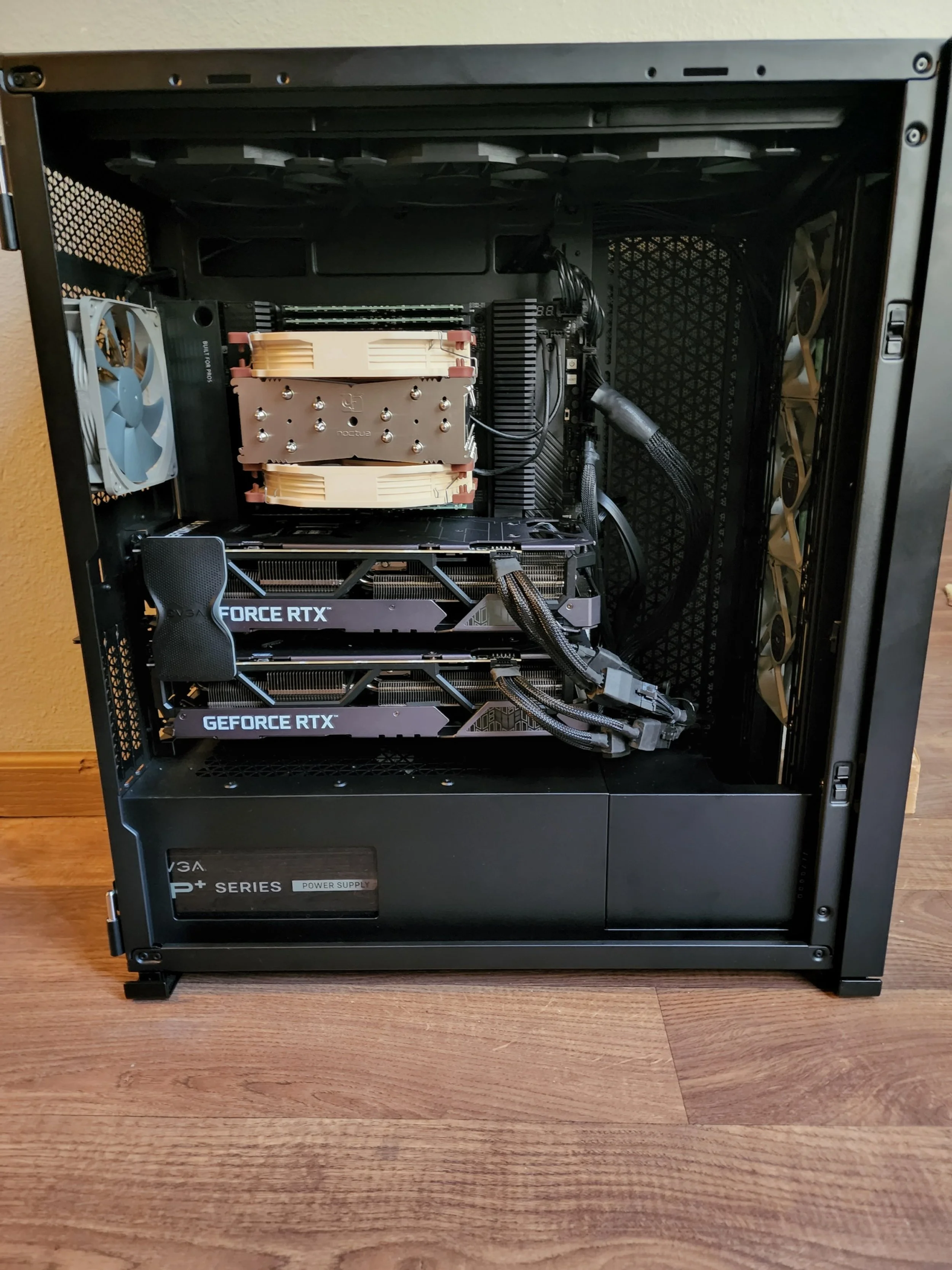 Open computer case showing internal components including two NVIDIA GeForce RTX graphics cards, a CPU cooler, a power supply unit, and case fans.