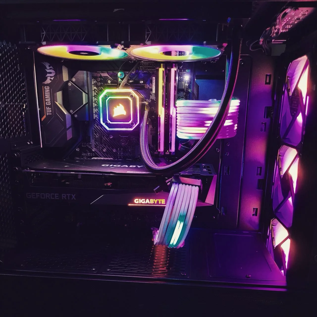Interior view of a gaming computer with RGB lighting, featuring a Gigabyte GEFORCE RTX graphics card, Corsair RAM modules, liquid cooling system, and multiple case fans with RGB lighting.