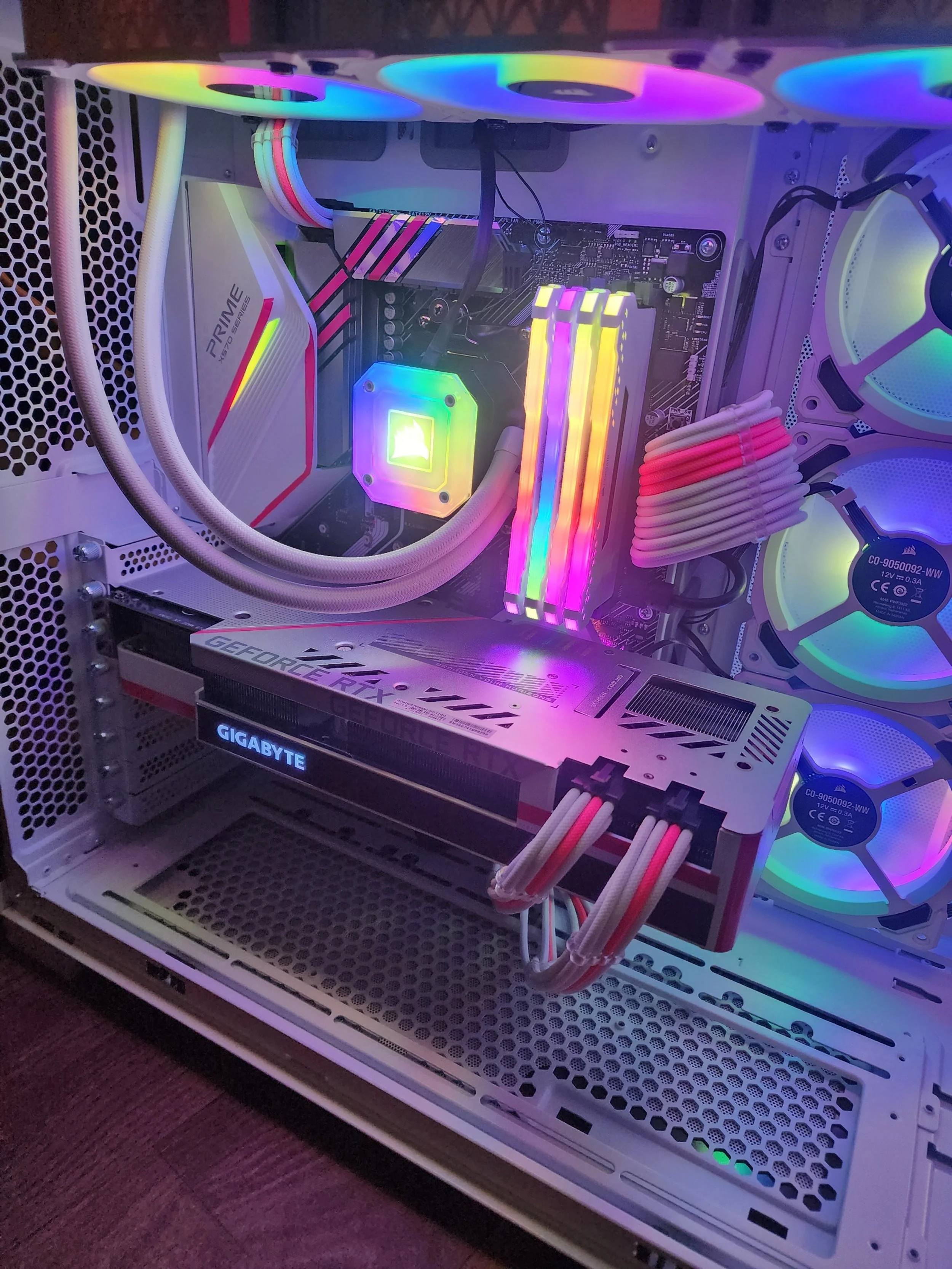 Interior of a high-performance gaming PC with illuminated RGB cooling fans, RAM sticks, and graphics card inside a white case.