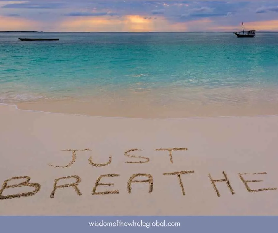 beach with Just Breathe written in the sand
