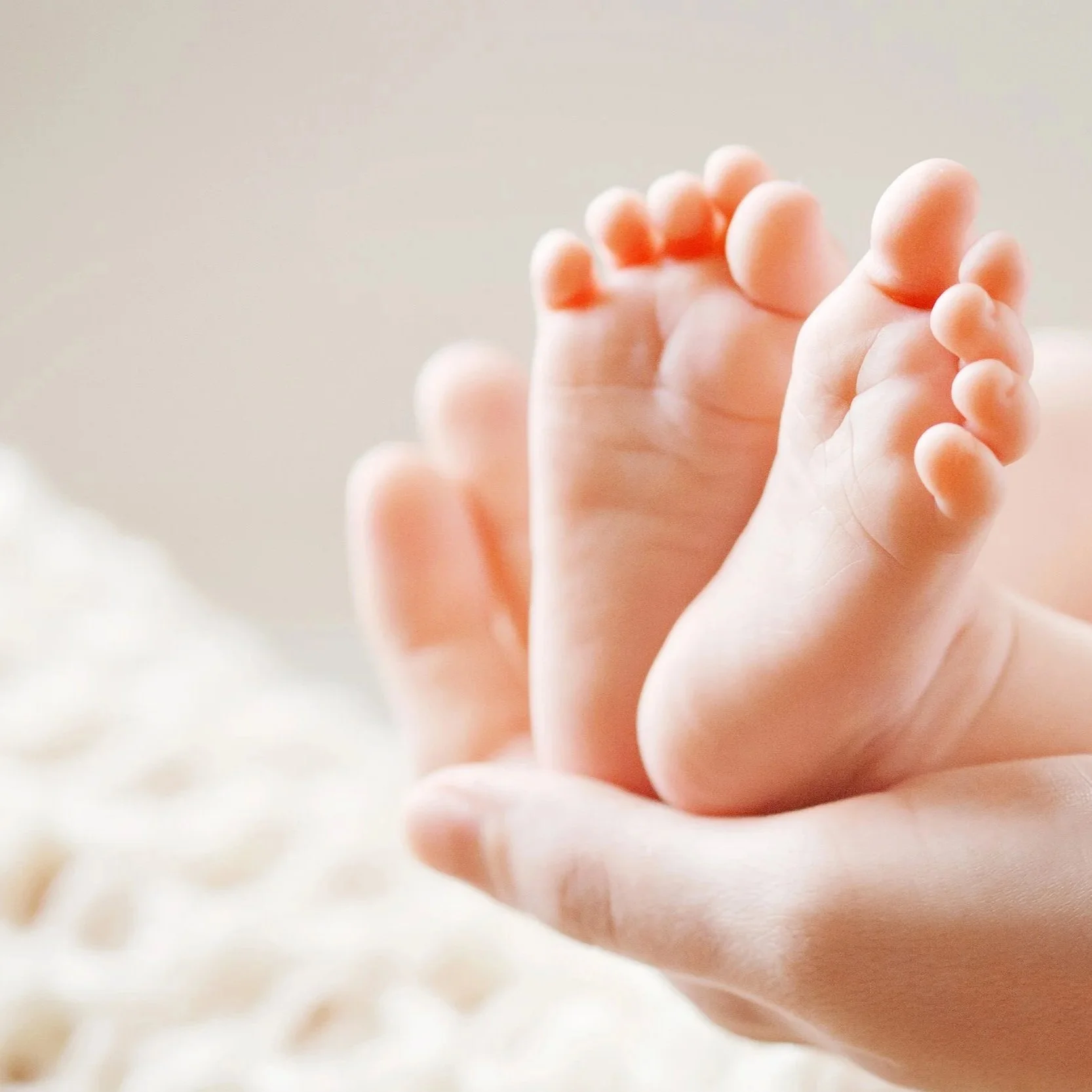 Nærbillede af en lille babys hånd, der holder om en voksen persons finger.