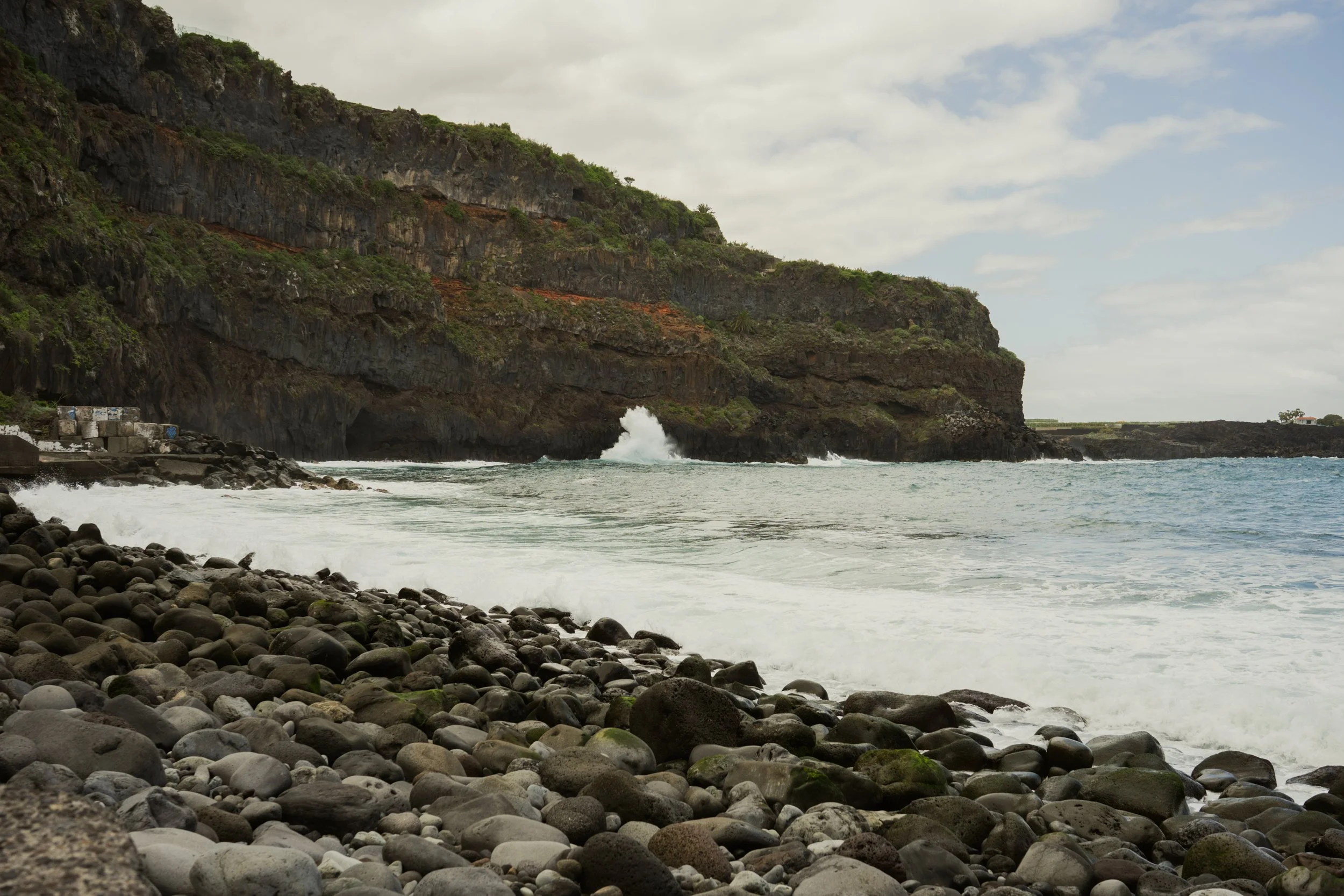 Beach with rocks and water splashing up the cliff