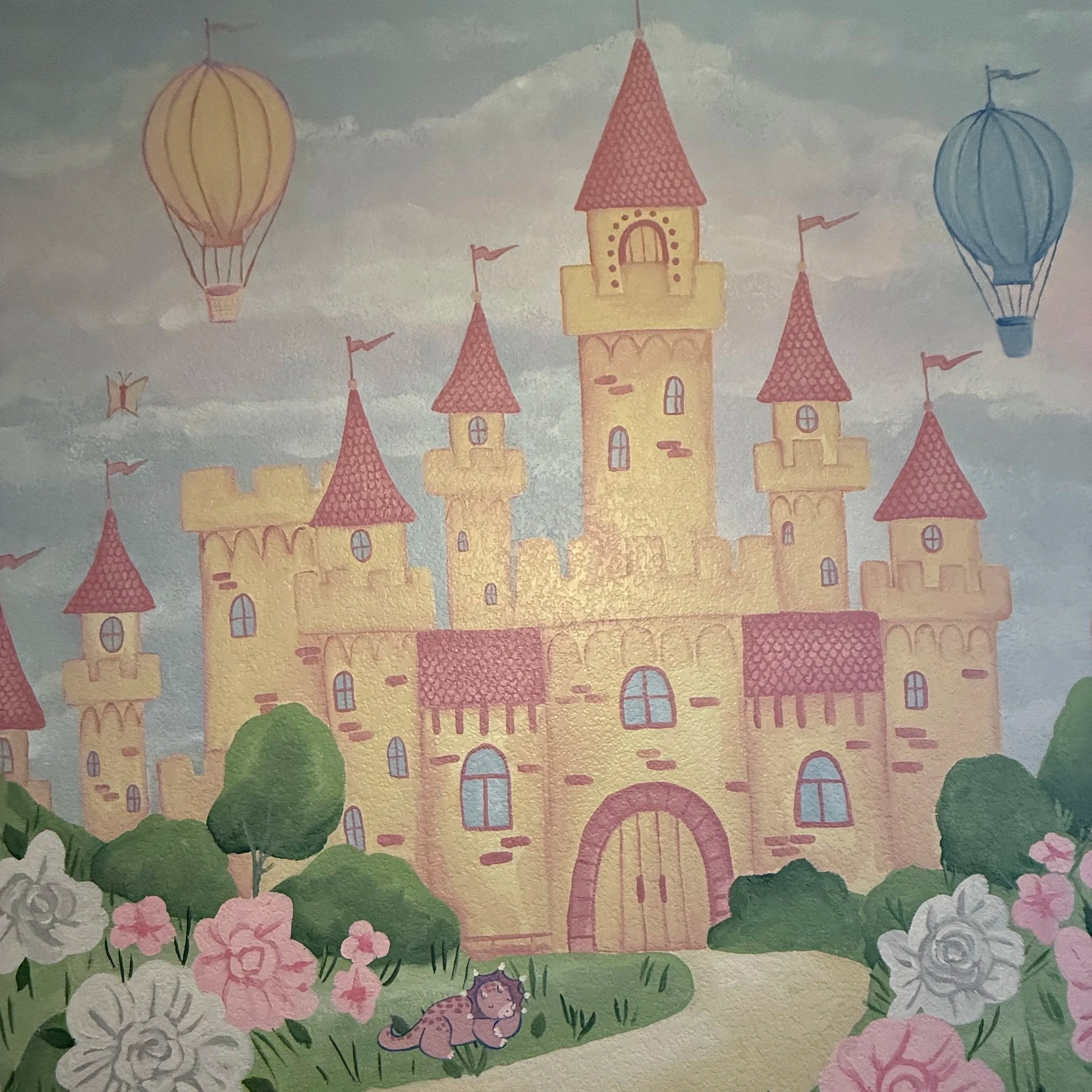 A colorful castle with pink roofs, surrounded by flowers and greenery. Two hot air balloons, one yellow and one blue, float in the sky. A lion sits among the flowers in the foreground.