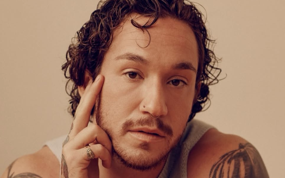 A brunette trans man with facial hair and tattoos.