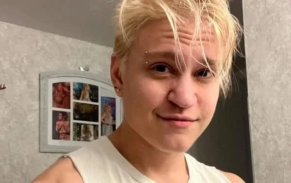 A white trans man with short blonde hair.