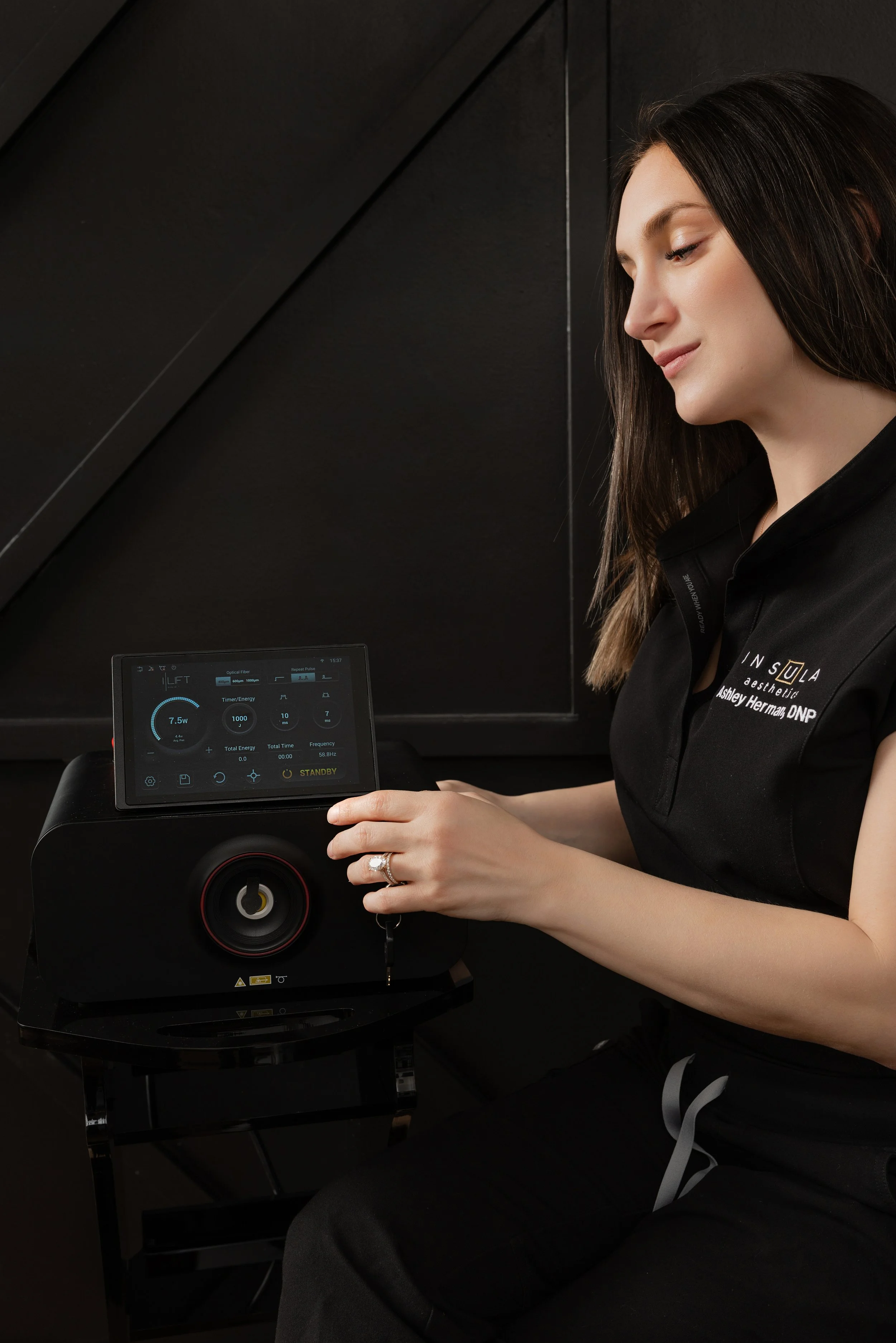 Dr. Ashley Herman adjusting settings on the iLaser 1940 Sculpt device touchscreen at Insula Aesthetics, showing energy and timer controls in standby mode.