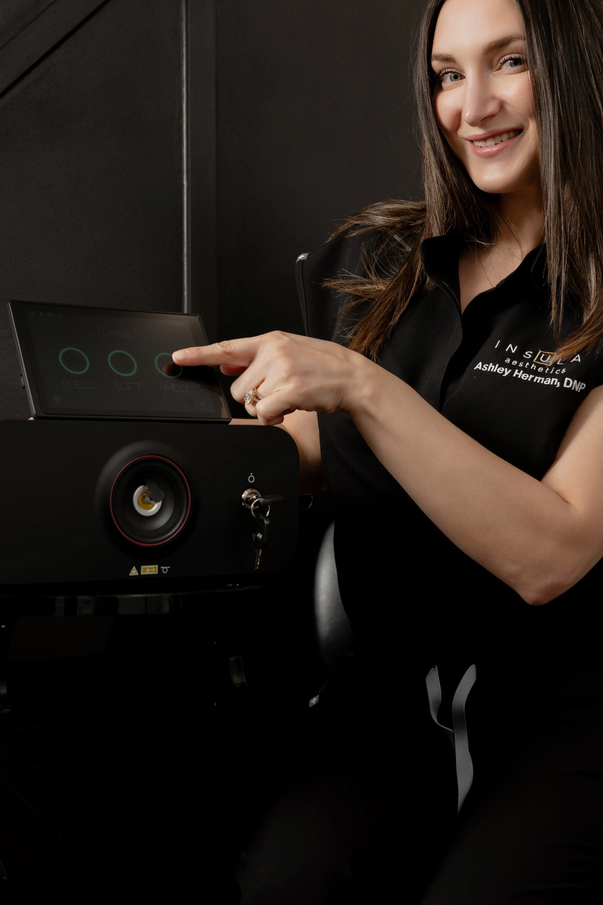 Dr. Ashley Herman smiling and selecting a treatment mode on the iLaser 1940 Sculpt touchscreen at Insula Aesthetics.