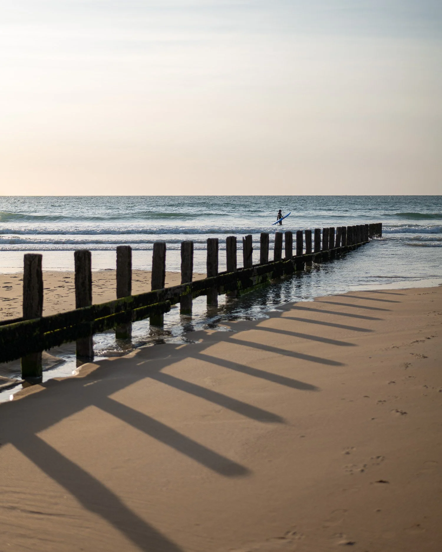 photo d'un surfeur à Saint-Malo, sur la cote d'émeraude porte sa planche.
