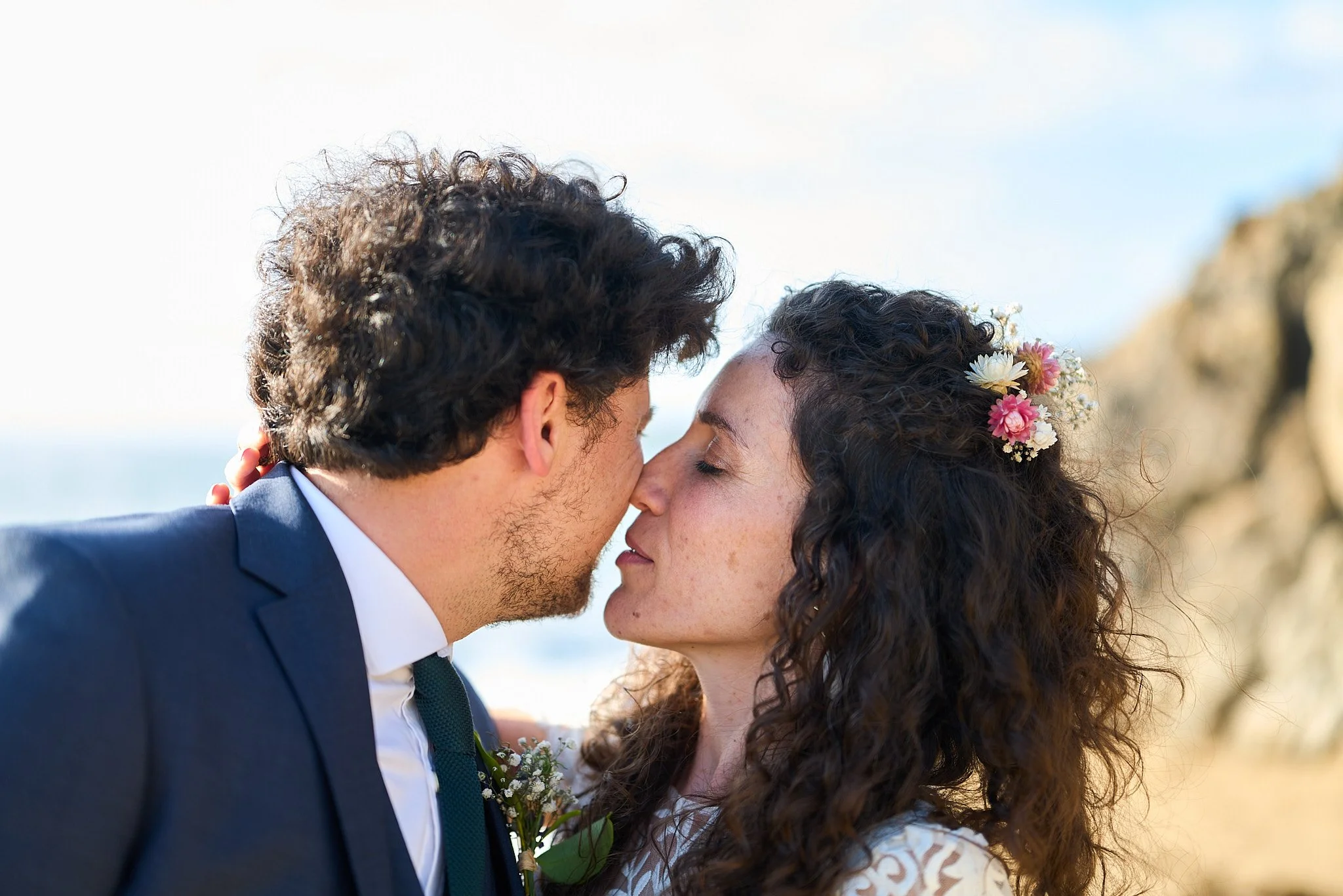 Un couple romance, la femme porte des fleurs dans les cheveux, près de la mer.