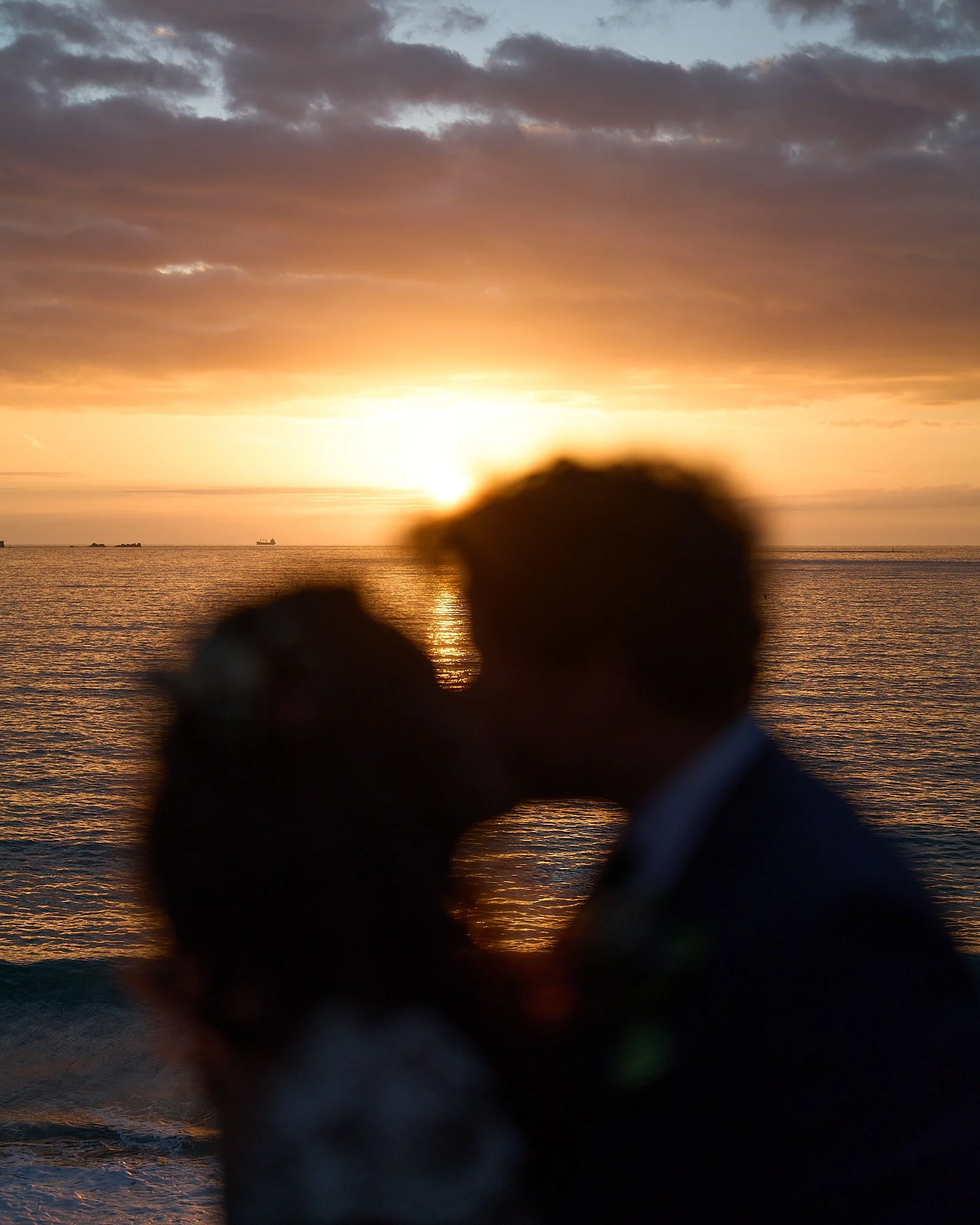 Silhouettes d'un couple s'embrassant au bord de la mer au coucher du soleil.