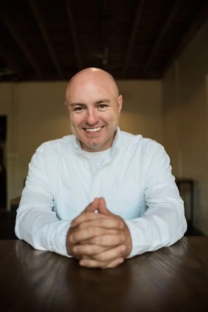 Modern wooden building with large glass window set against a mountainous landscape.