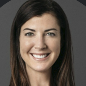 A smiling woman with long dark hair, wearing a black top and a necklace, against a gray background.