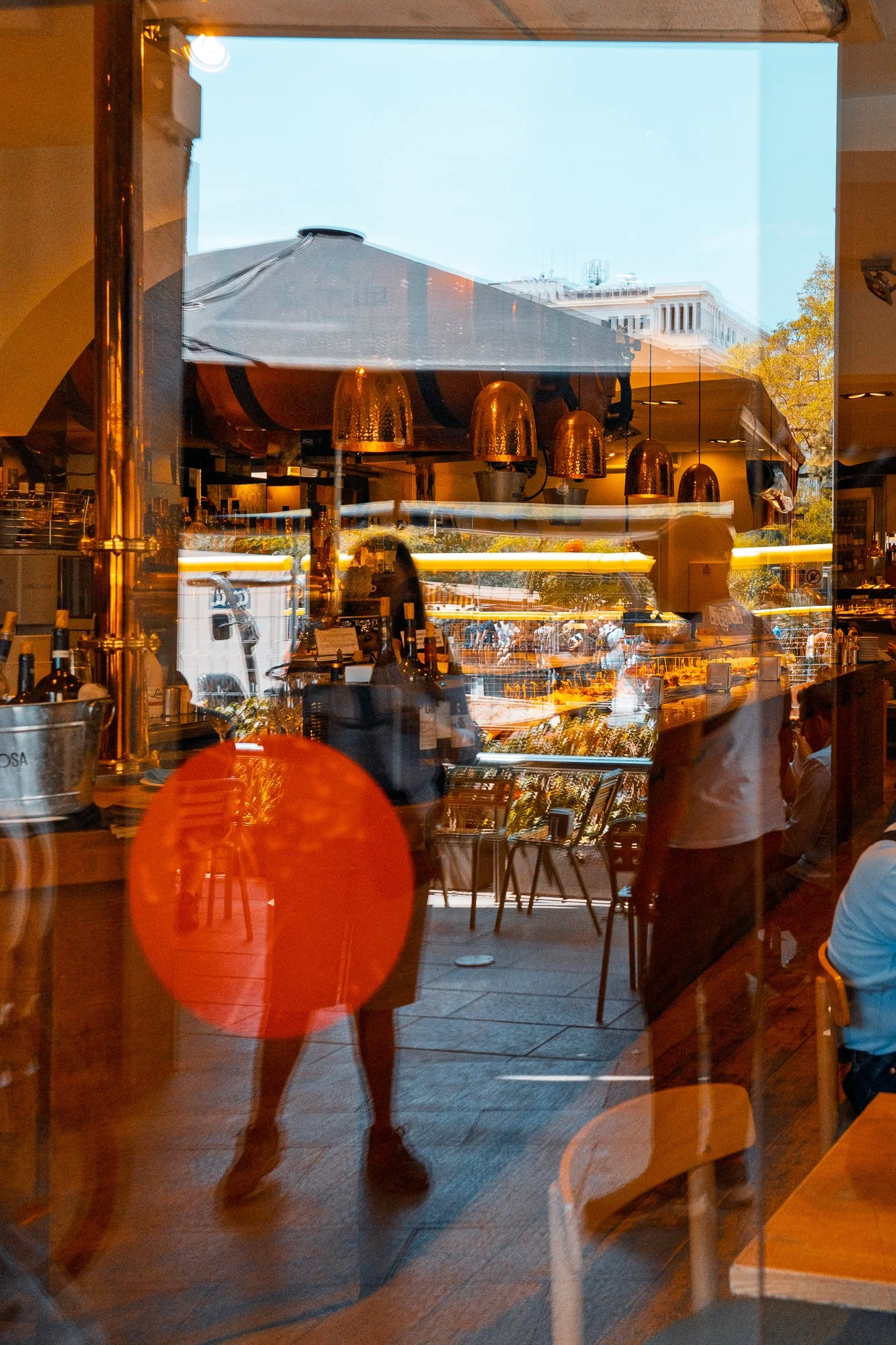 Orange circular reflection over a bar interior, street photography in Barcelona – bCLPhoto