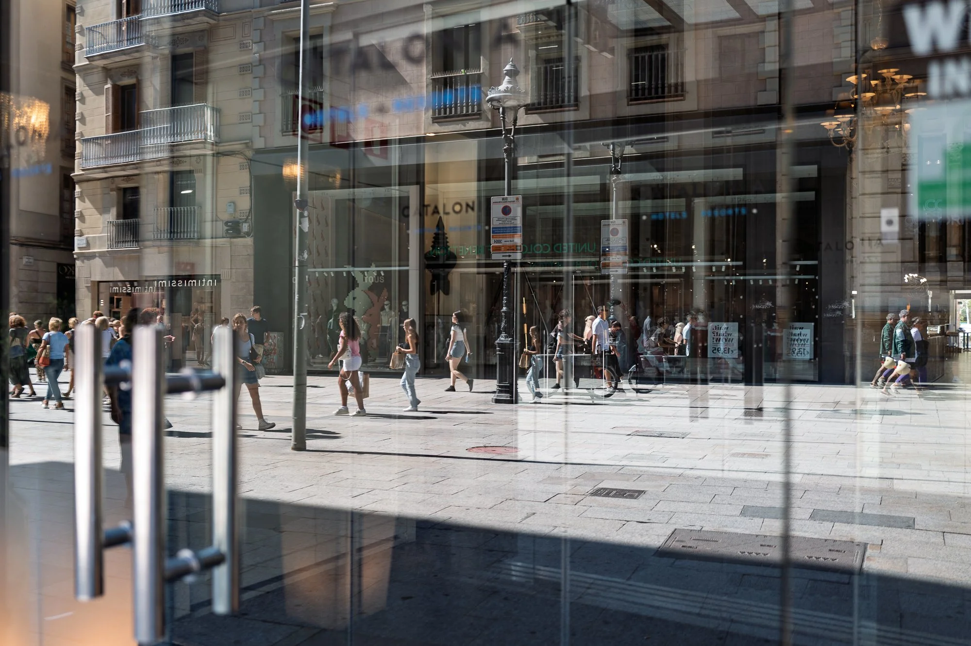 Pedestrians multiplied in a glass reflection outside a hotel, street photography in Barcelona – bCLPhoto