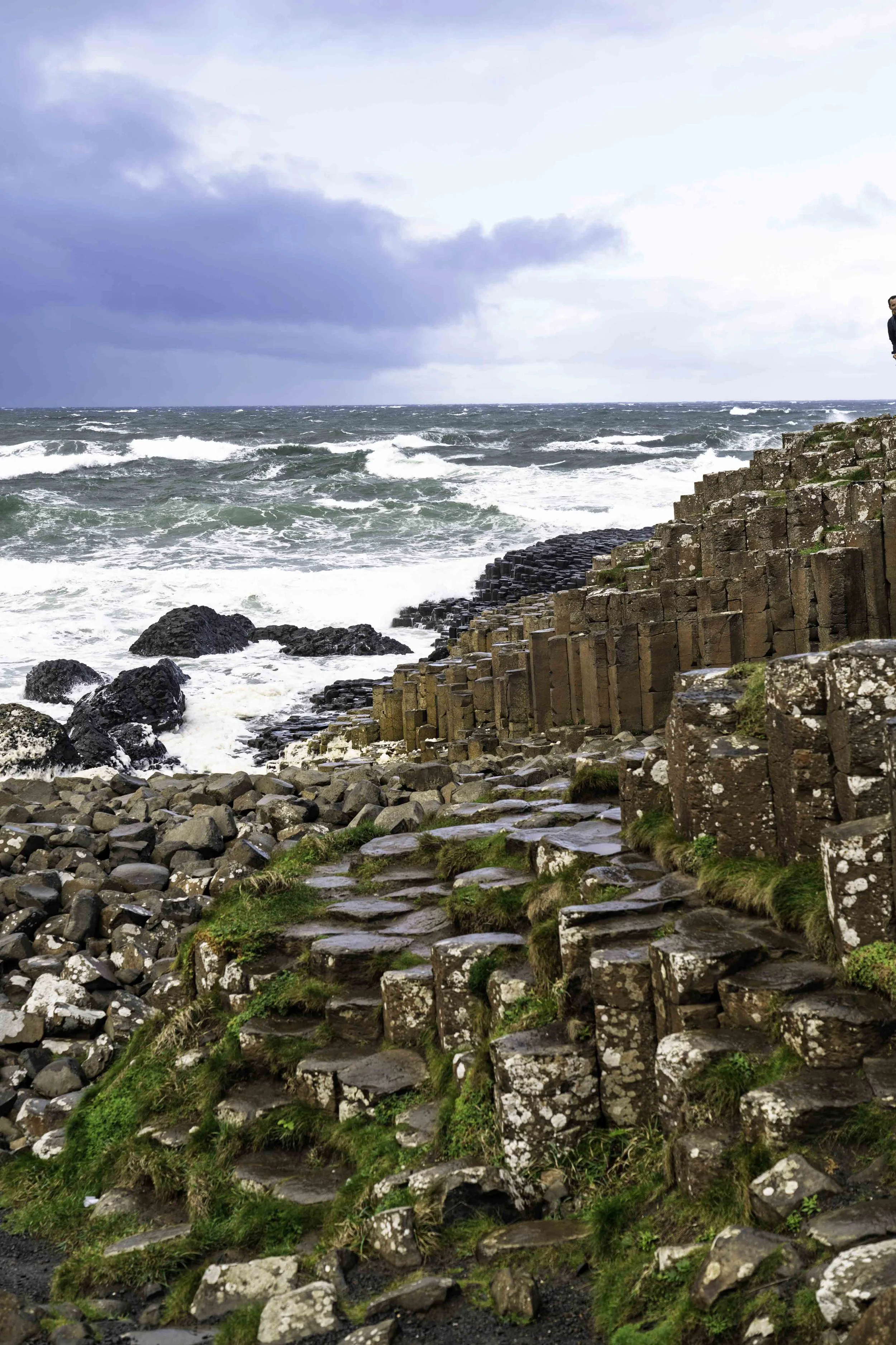 Moss-covered basalt columns at Giant's Causeway with stormy Atlantic waves and dramatic storm clouds, Northern Ireland – bCLPhoto