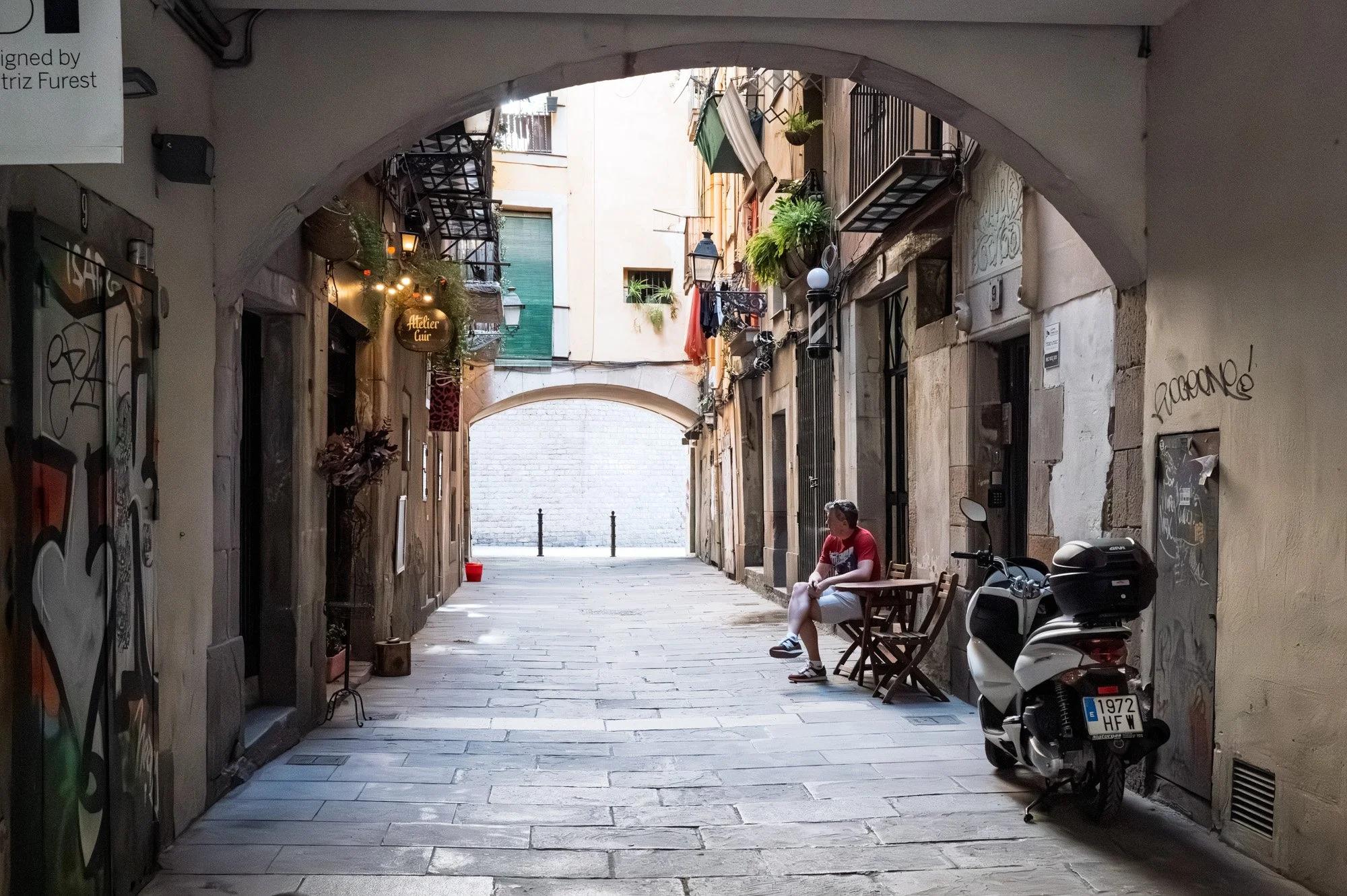 Alt text: Man with scooter under stone arcade, El Born Barcelona — Leica Q3