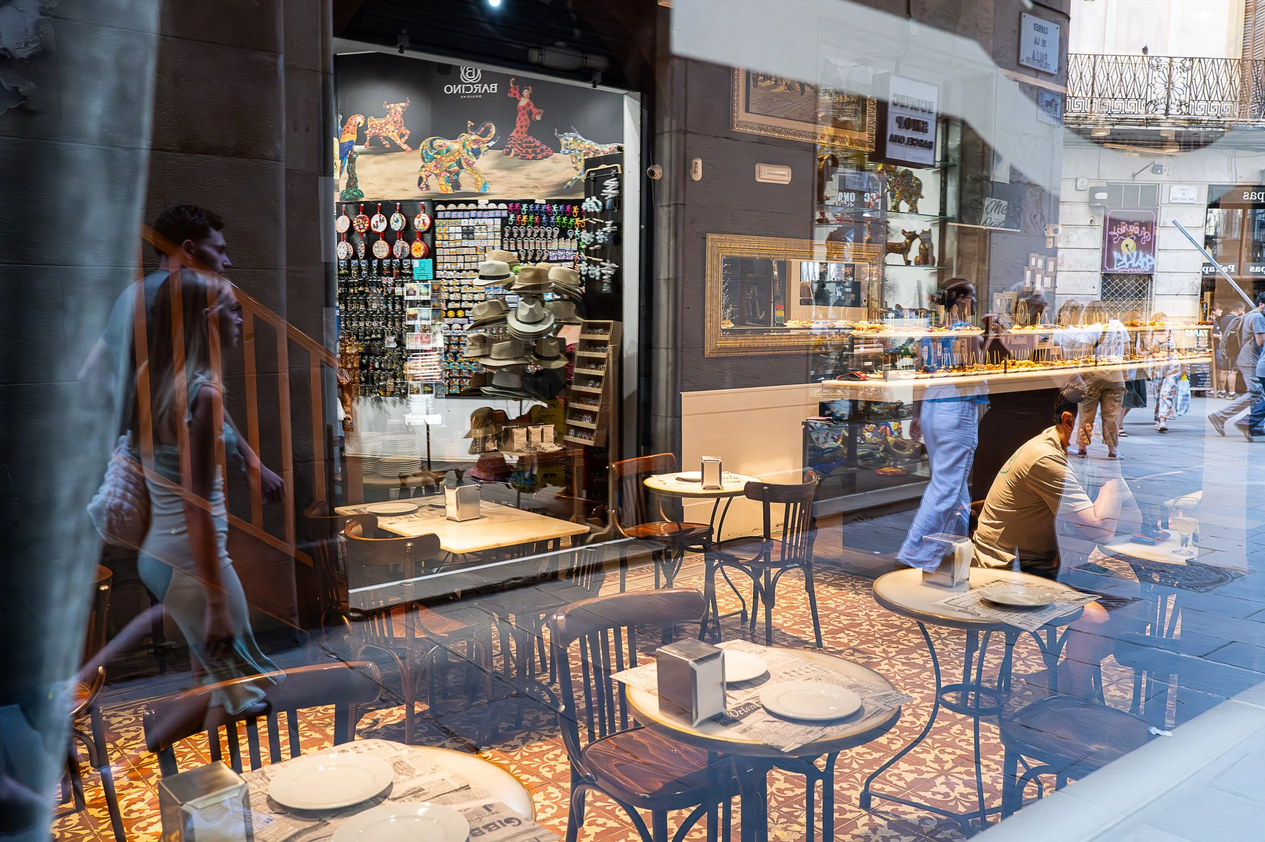 Reflections of people on the street and shops across the way in the window of a bar and a view of the interior, Street photography in Barcelona – bCLPhoto