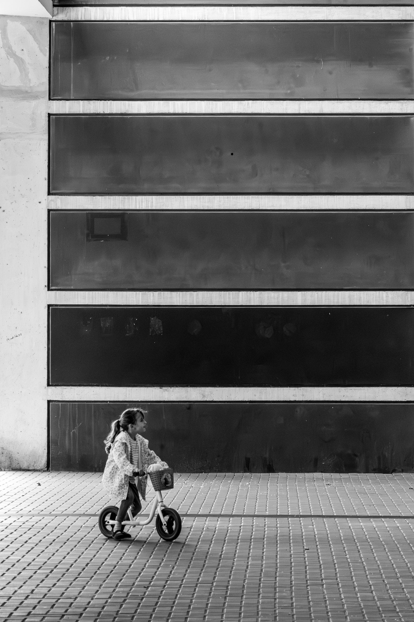 Girl on balance bike past mirrored facade, Barcelona — Sony A7R IV