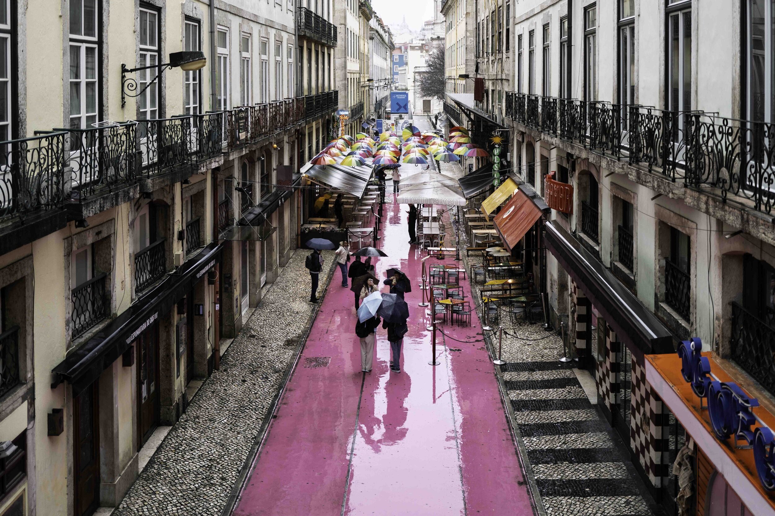 Rainy day on Rua Nova do Carvalho, Pink Street, Lisbon street photography with reflections and umbrellas — Leica Q3