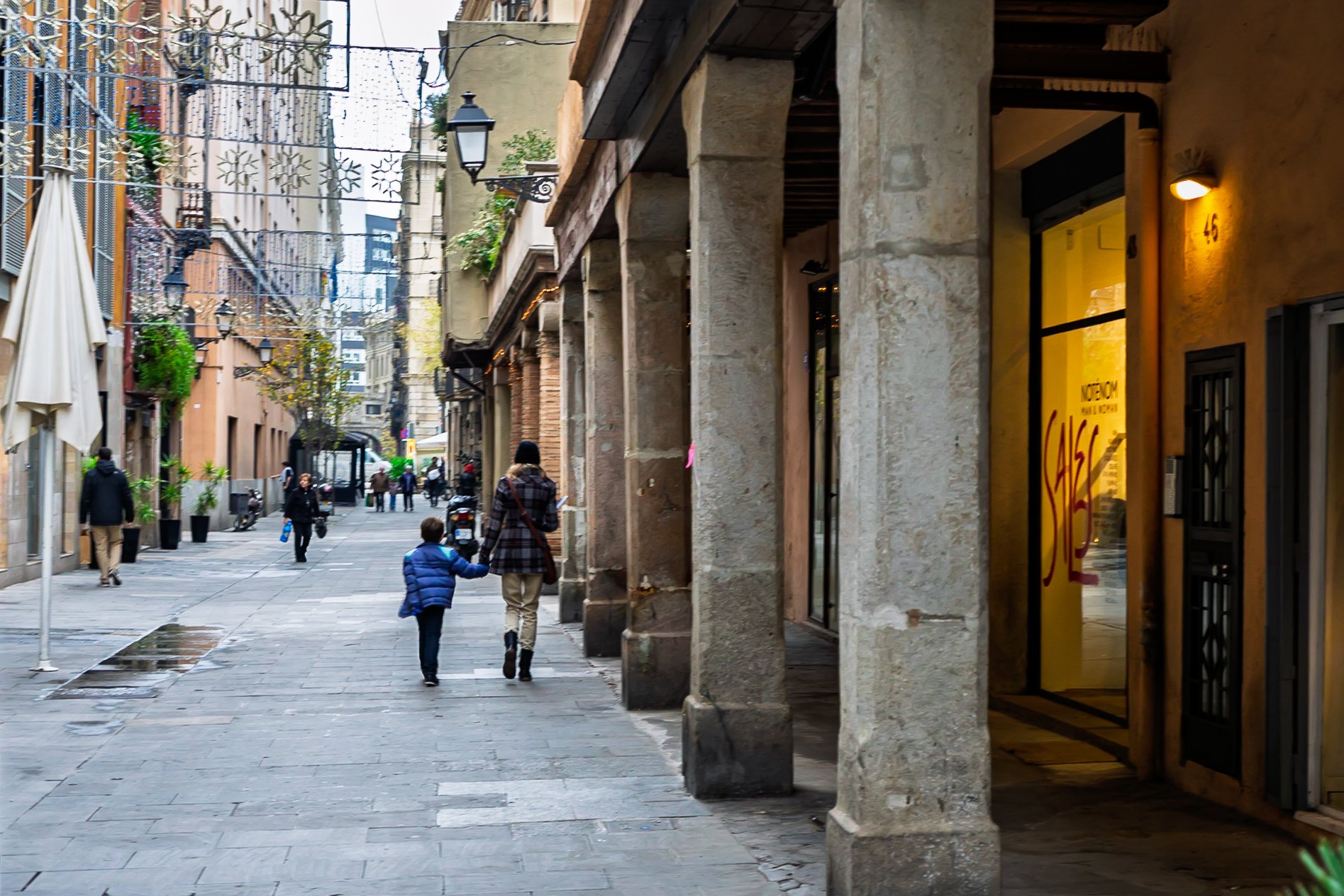 Mother and son crossing under the porticoes, El Born street photography, Barcelona — Leica Q3