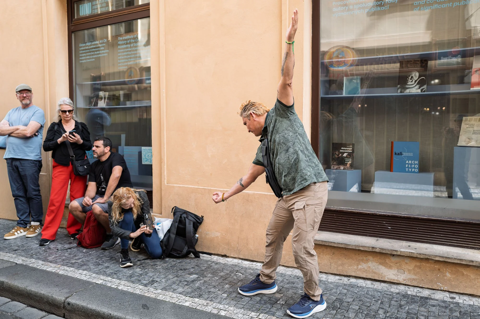 Man on the pavement pretending to hold up the hanging Freud sculpture, Prague — Leica Q3
