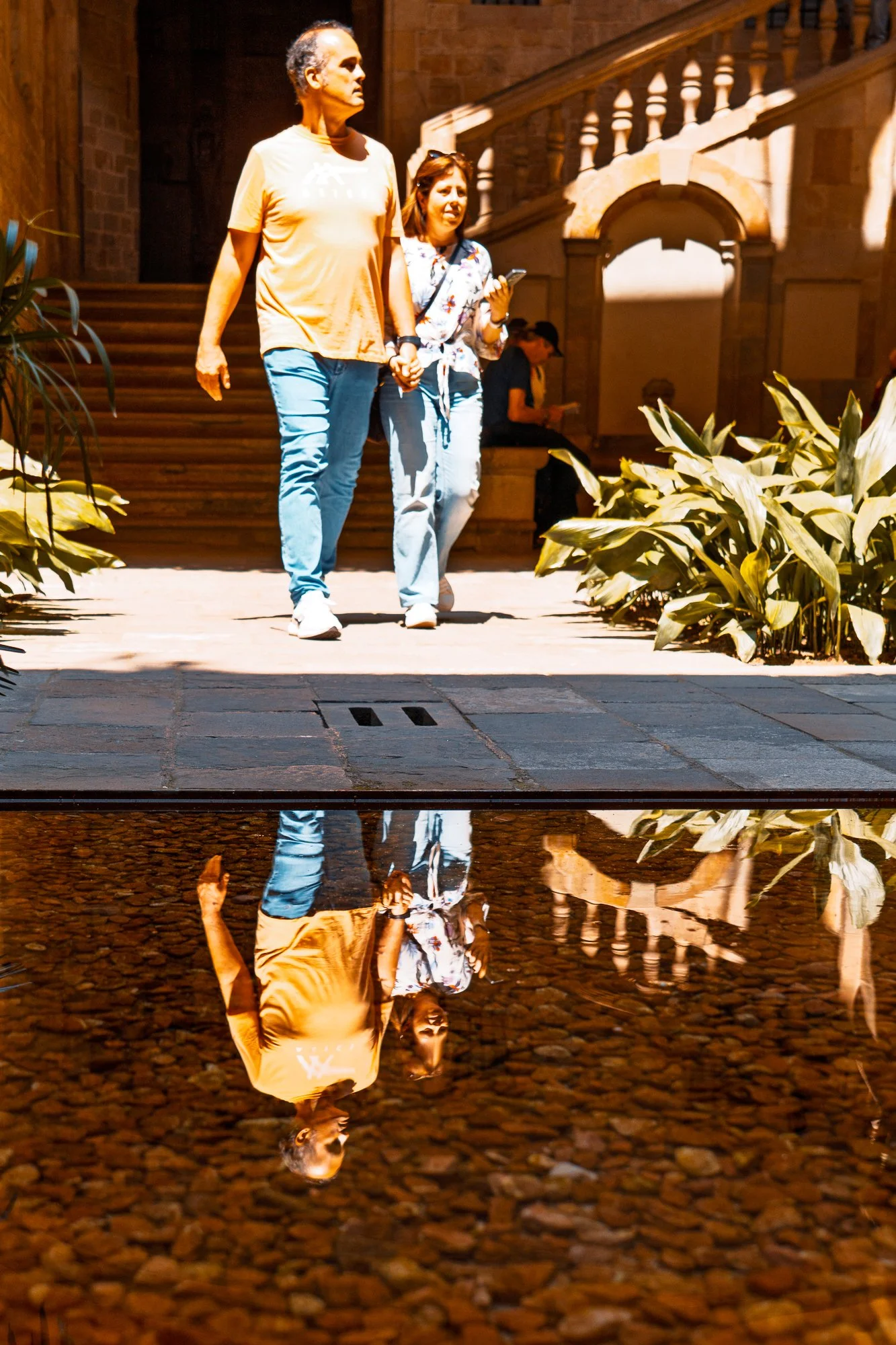 Couple holding hands reflected in a puddle, street photography in Barcelona — Sony A7R IV
