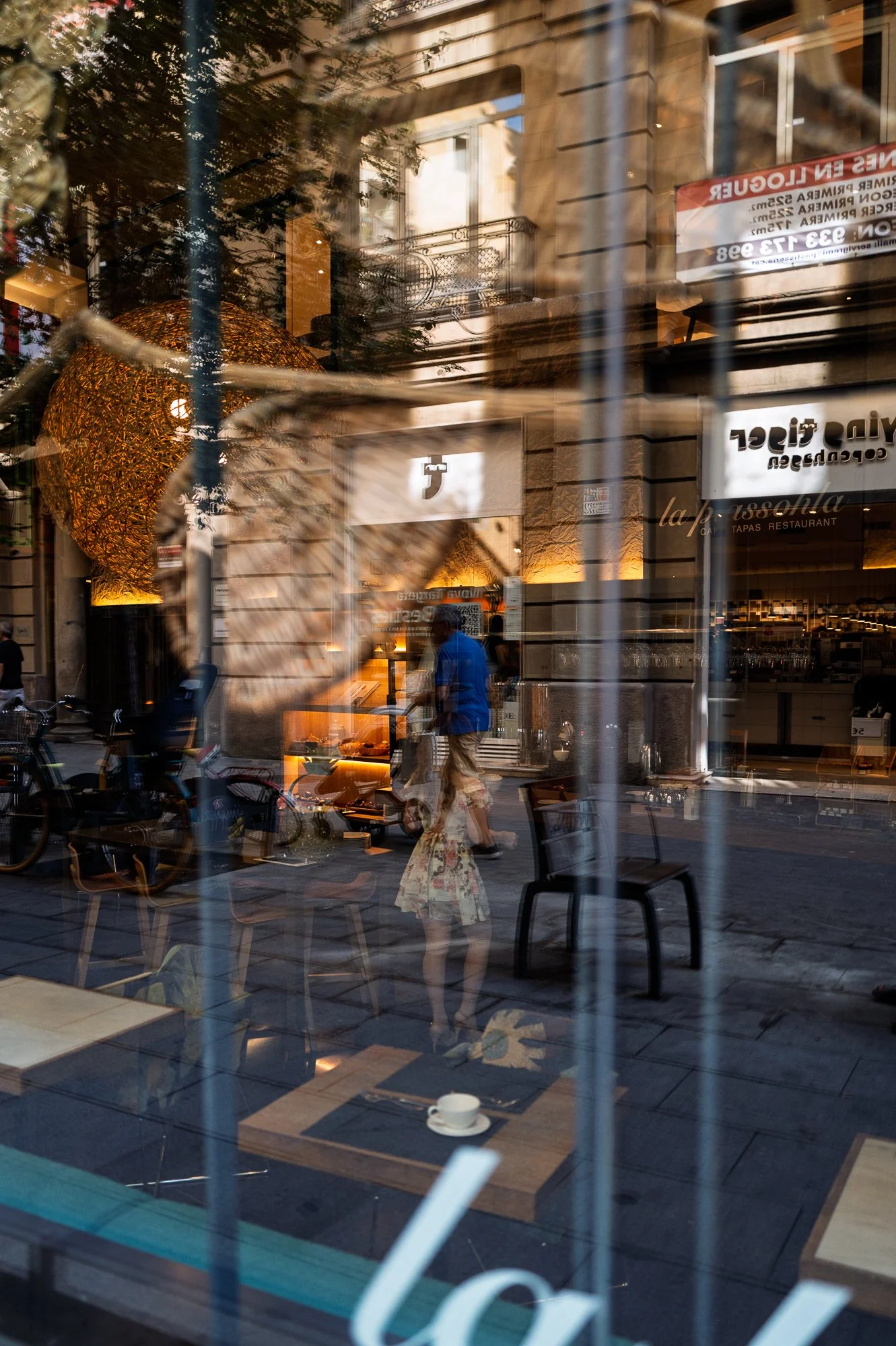 Woman in a floral dress reflected outside a restaurant, street photography in Barcelona – bCLPhoto