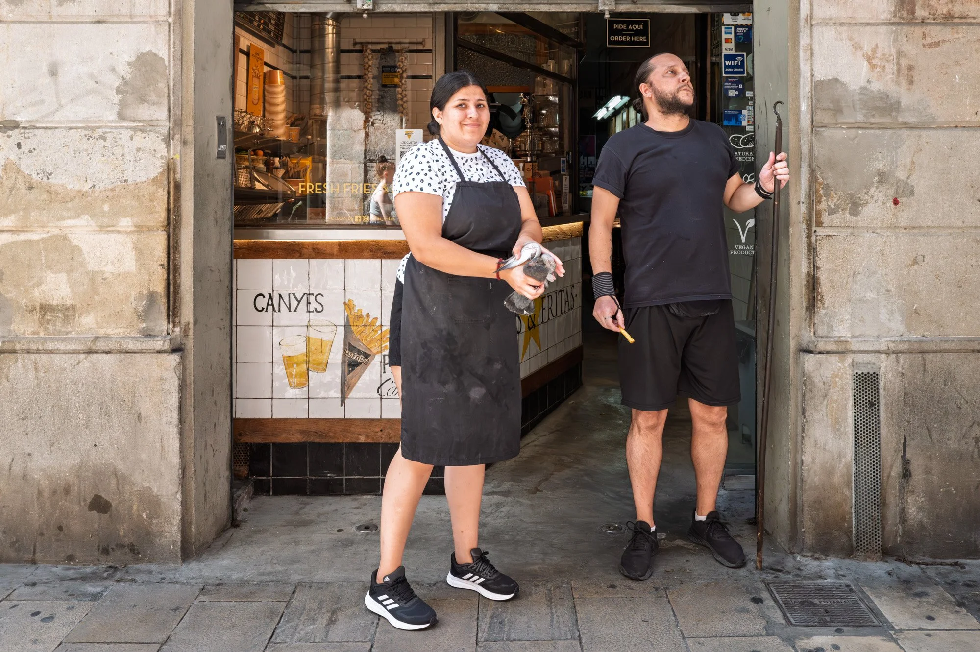 Woman holding a pigeon by hand outside a fries shop, El Born, Barcelona — Leica Q3