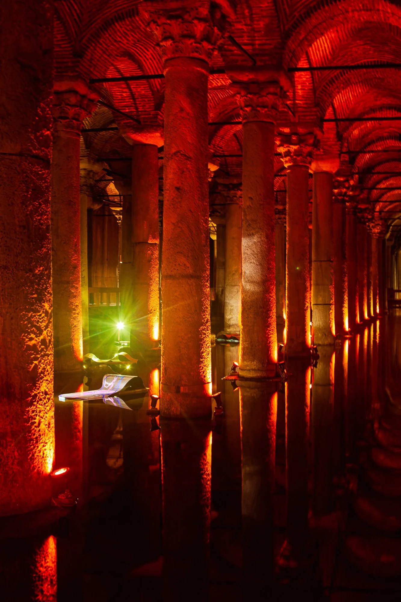 Red-lit columns with carved capitals and a painted white sheet floating on the water, Basilica Cistern, Istanbul