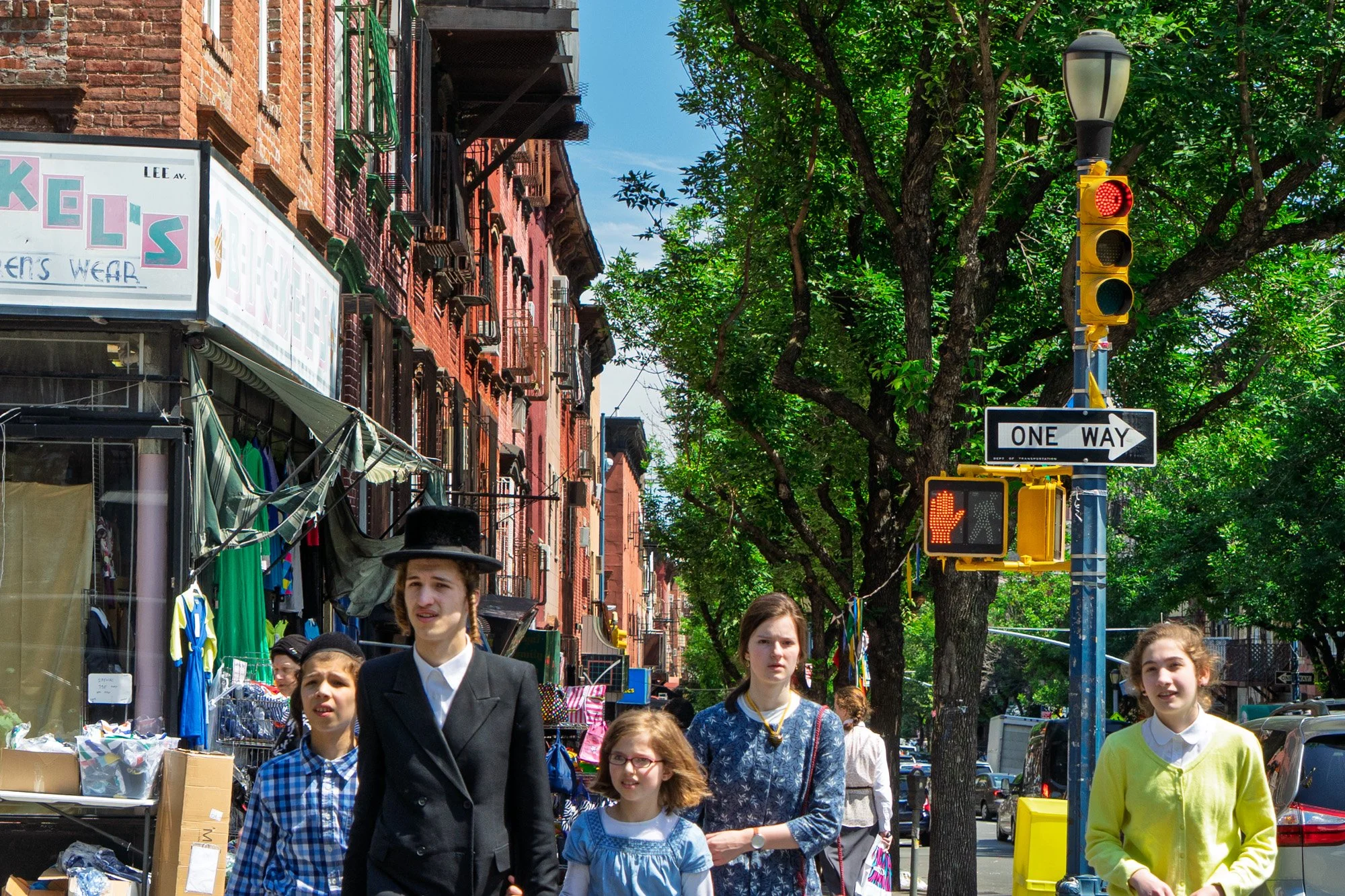 Hasidic family walking on Lee Avenue with brownstones and One Way sign, South Williamsburg — Sony a7II