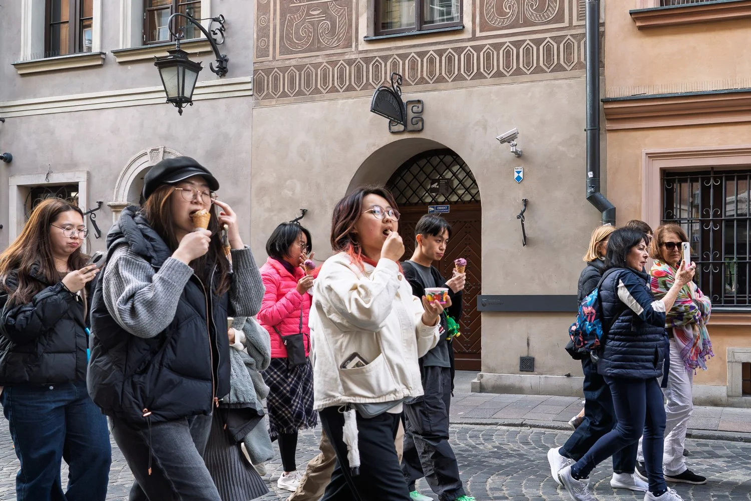 Young travellers eating ice cream past a sgraffito-decorated façade in Warsaw Old Town — Sony a7R IV