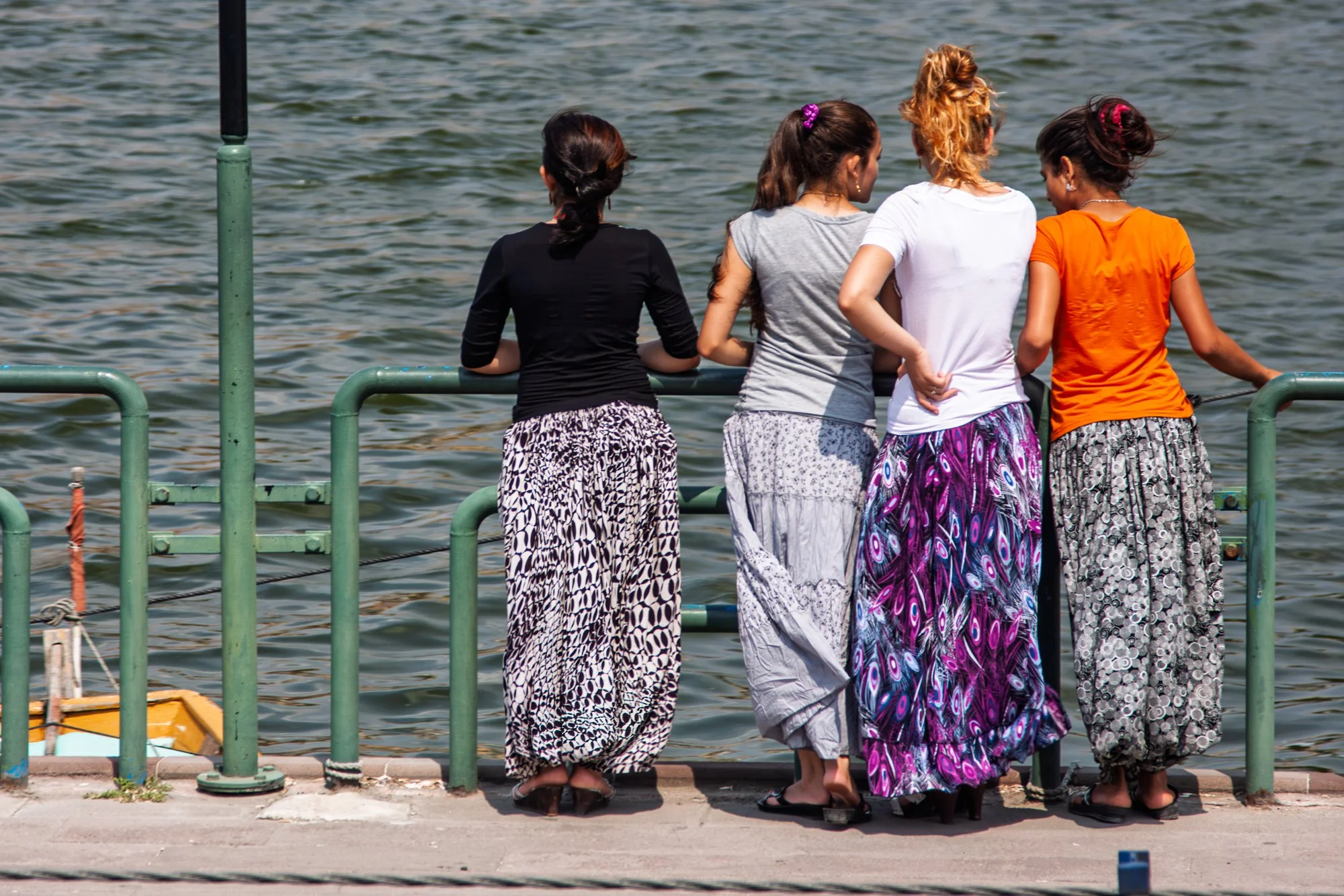 Four young women in patterned harem trousers at a waterside railing, seen from behind, Istanbul — Canon EOS 40D