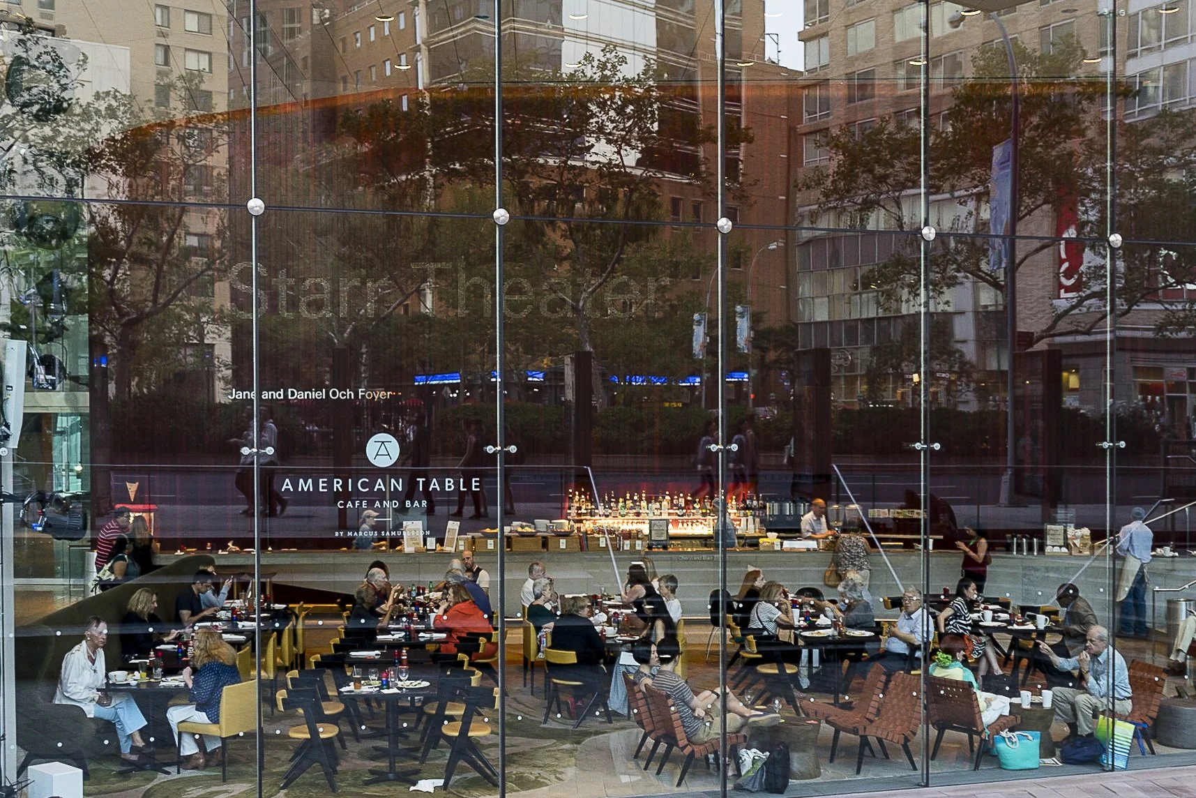 Manhattan reflected in a huge glass window with a lively gathering of clients and the bar in the background – bCLPhoto