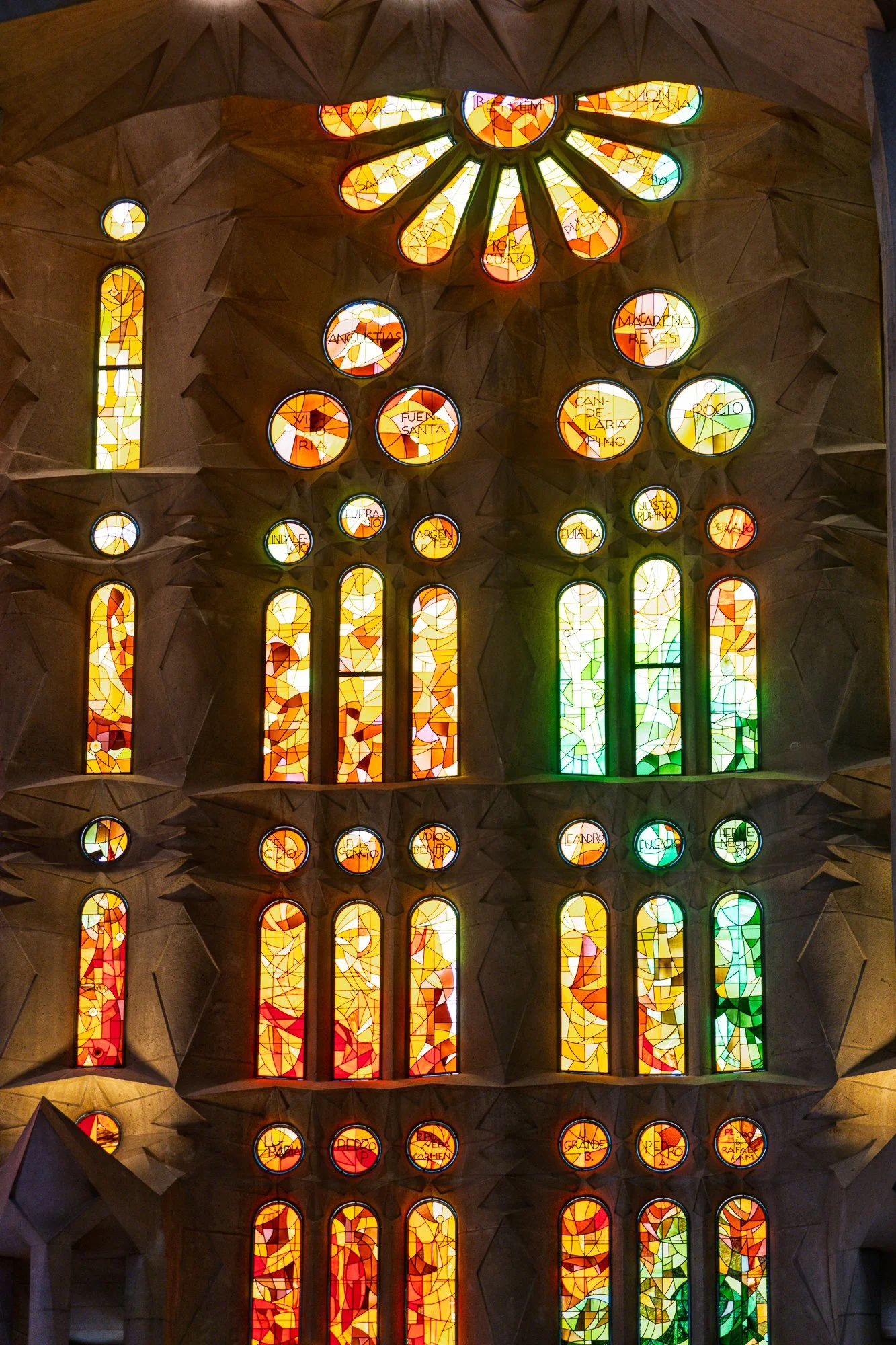 Warm-toned stained glass windows inscribed with saints' names, Sagrada Família — bCLPhoto