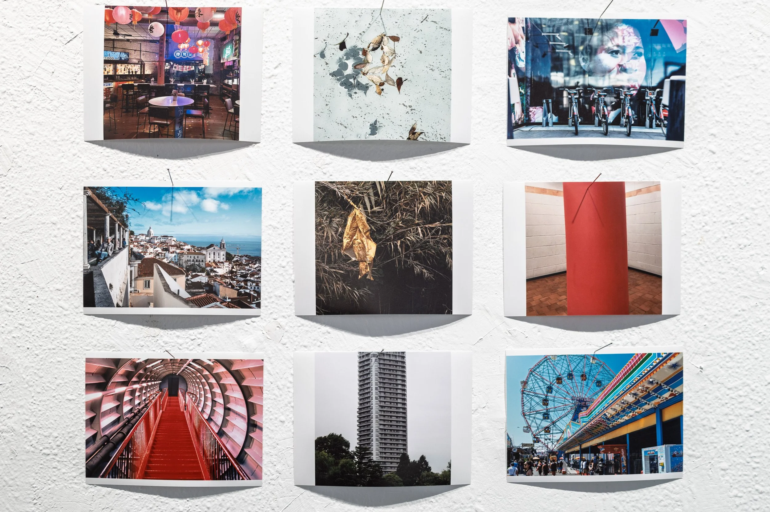 Nine small prints pinned to a white wall, red tones and a gold sheet in reeds, espai[b] Barcelona — Leica Q3