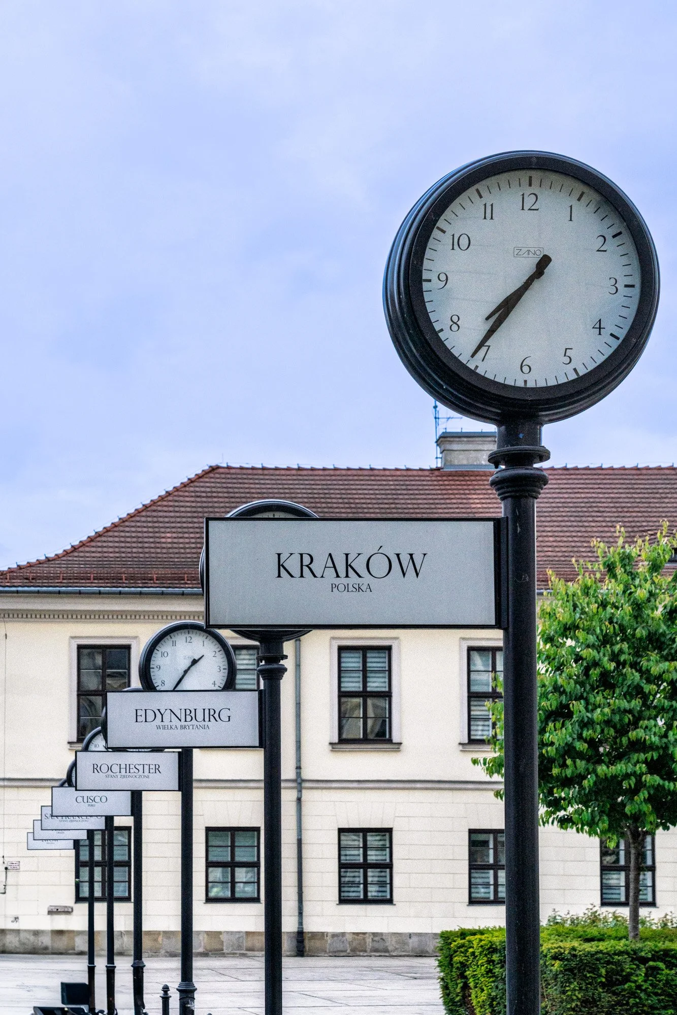 Street clocks showing world cities including Kraków, Edynburg and Rochester in a square, Kraków, Poland — bCLPhoto