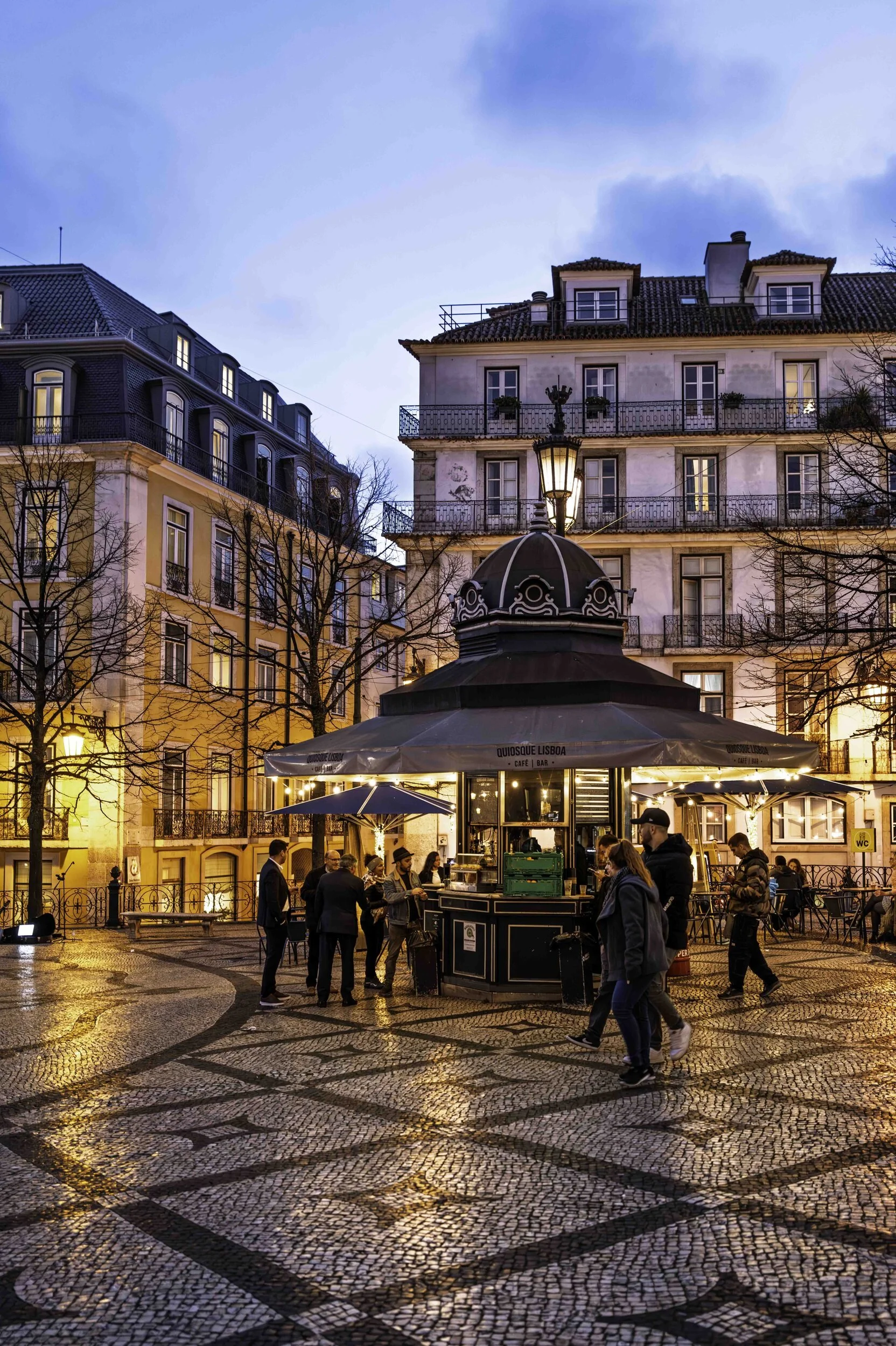 Evening kiosk in a Lisbon square, cobblestone mosaic at dusk, Chiado street photography — Leica Q3